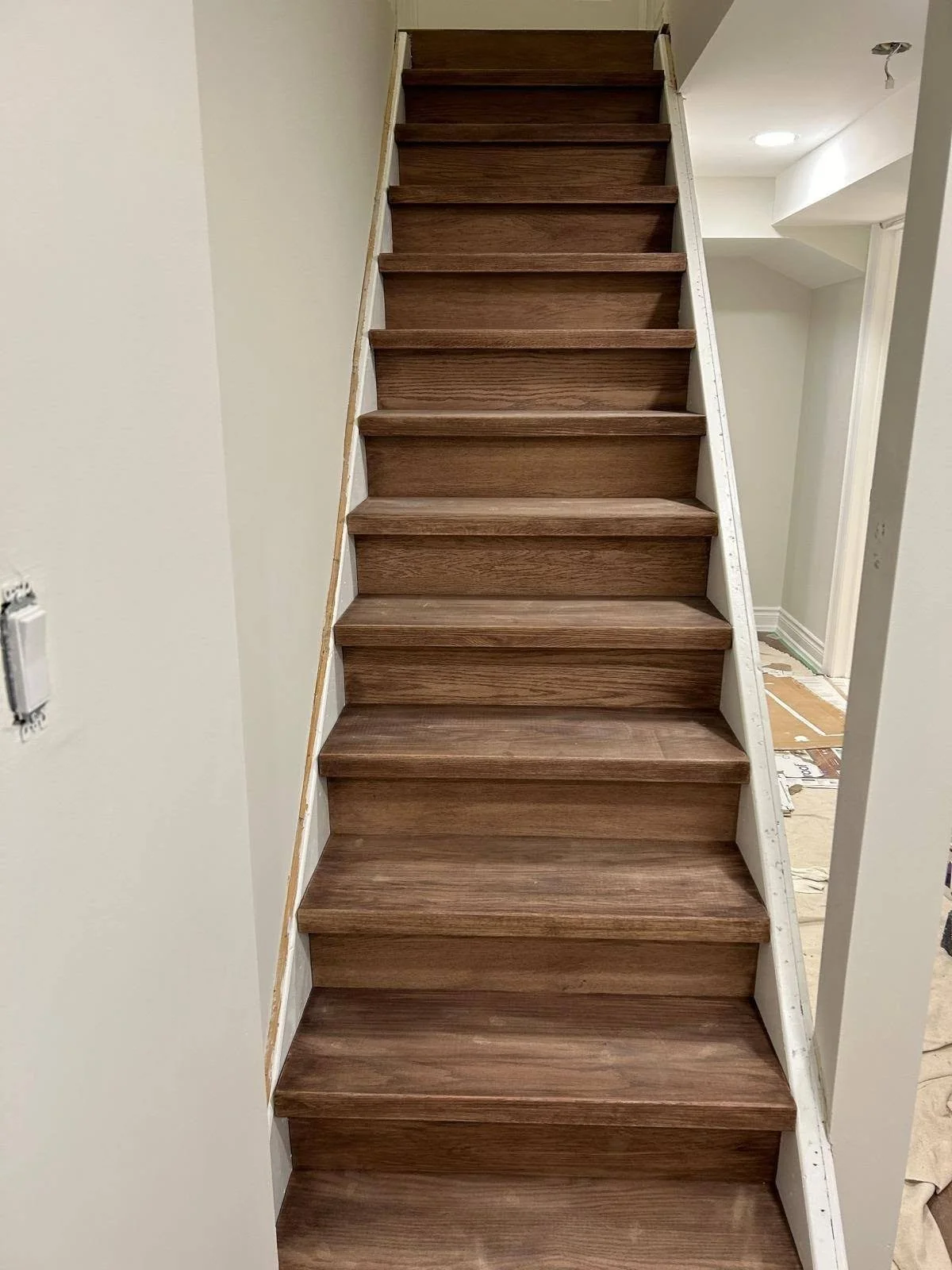 Finished interior staircase renovation with dark brown wood-look stair treads and matching risers.