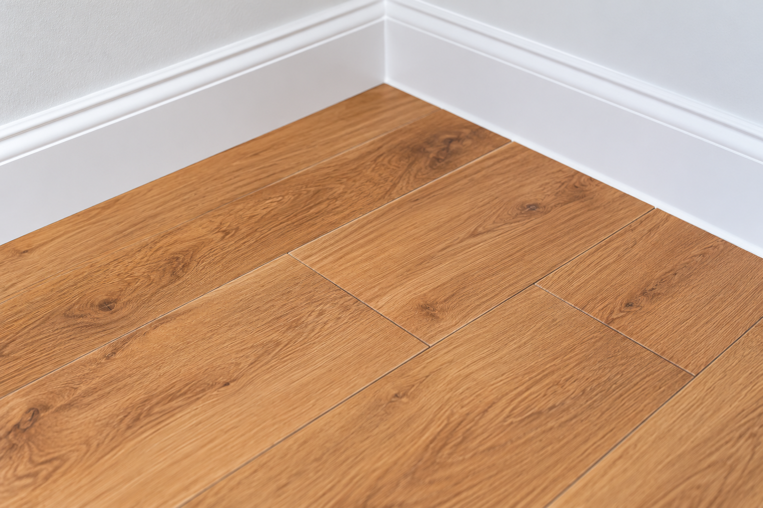 Wood-look plank flooring with white baseboards and trim in a residential interior.