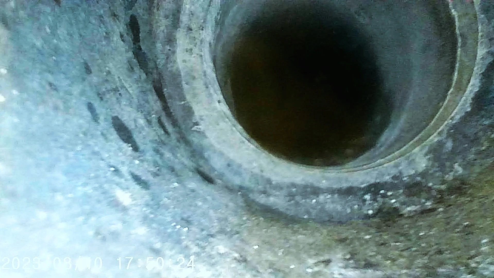 Close-up view of a large pipe with circular opening and textured, concrete inner surface