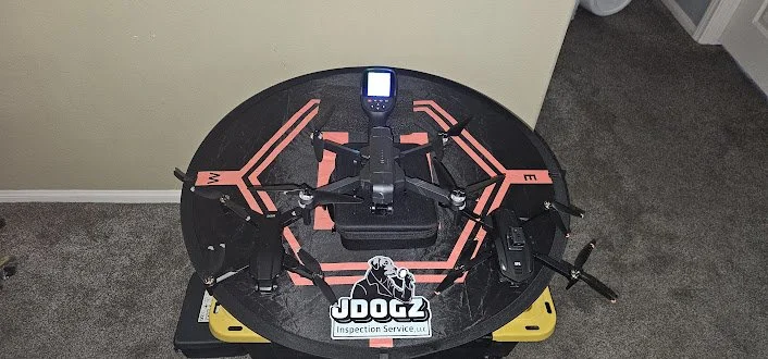 Drone on a black circular landing pad with red markings, remote control, and DJI drone logo on a table.
