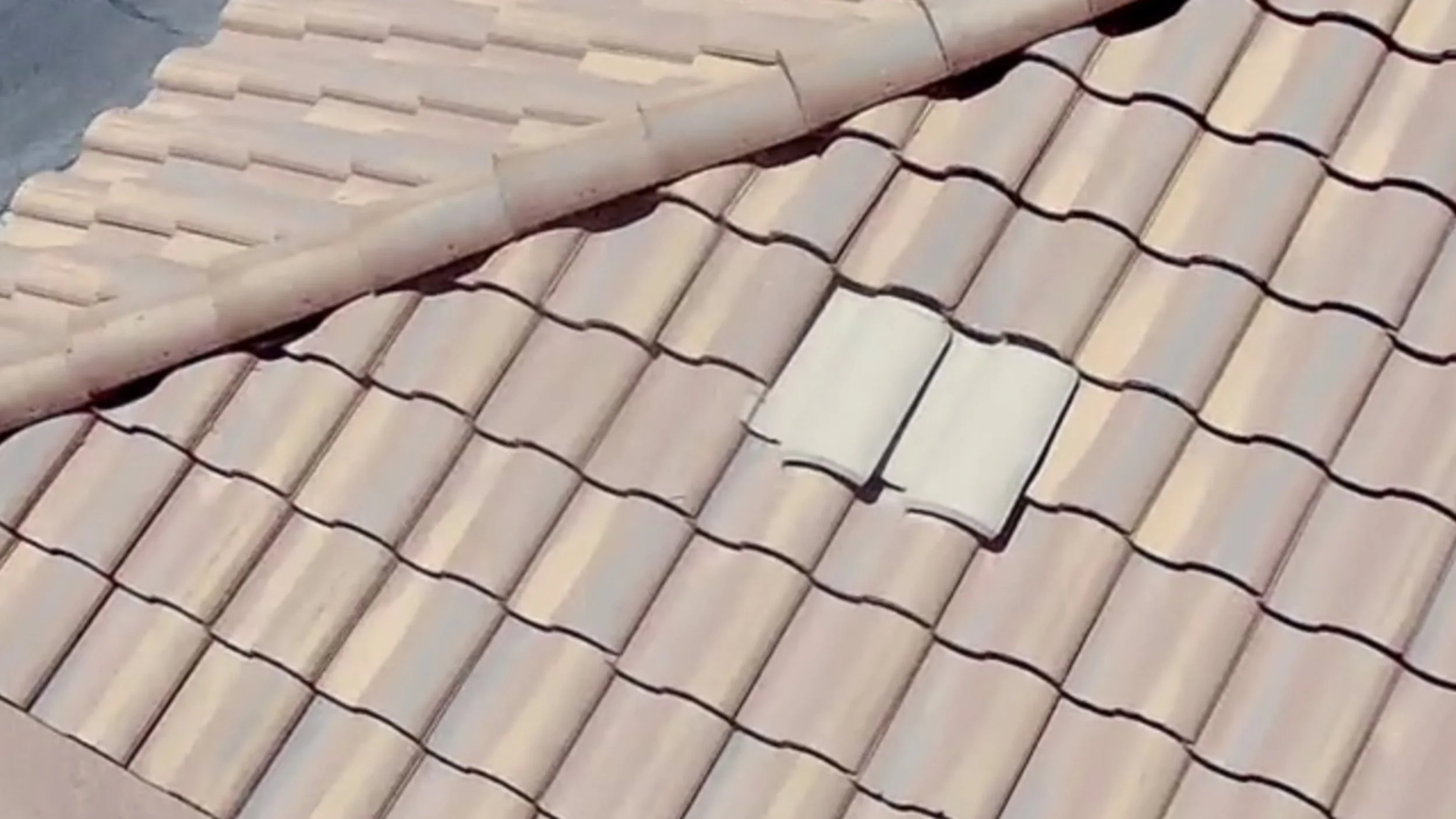 Close-up view of beige ceramic roof tiles arranged in overlapping rows.