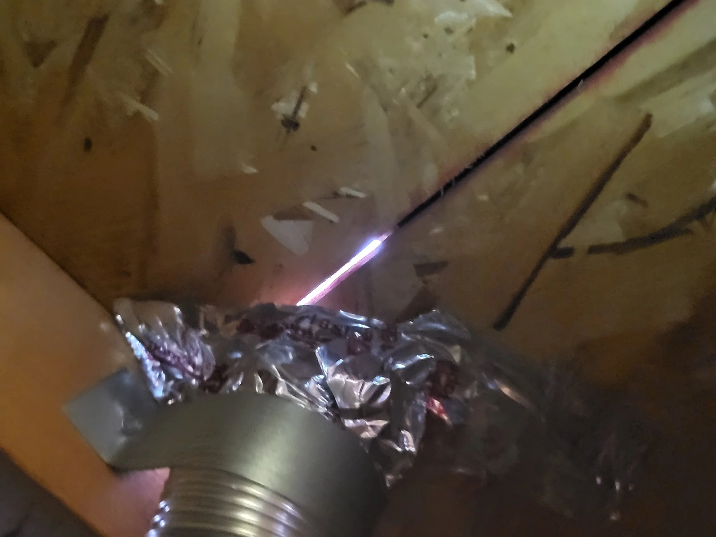 in an attic space showing a defective roof penetration to the exterior for a vent pipe, seeing daylight through the roof boards with insulated tape holding it together while the tape is failing and unravelling,