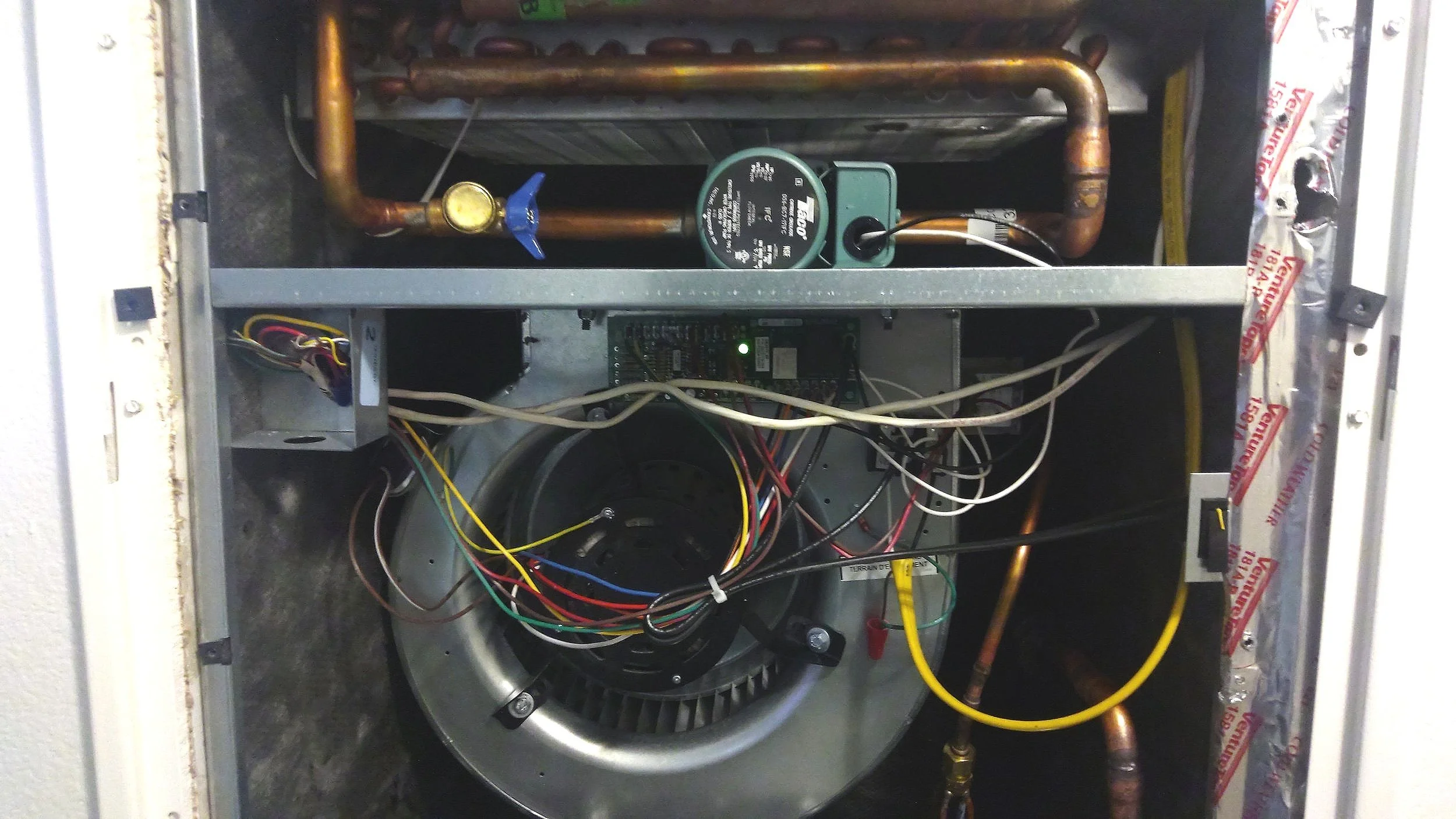 Modern horizontal hydronic water circulation lines and blower fan for residential heating and cooling.