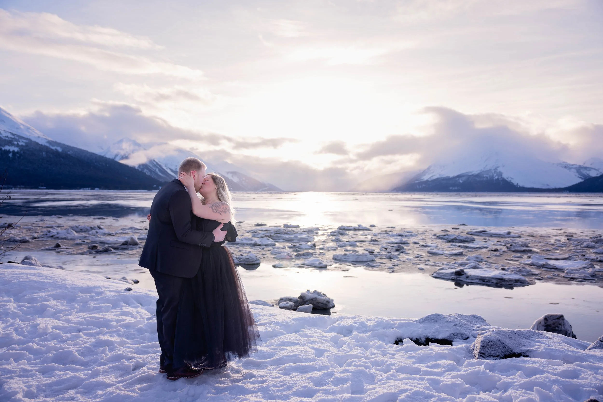 Elopement couple kissing by the water in Alaska in the winter