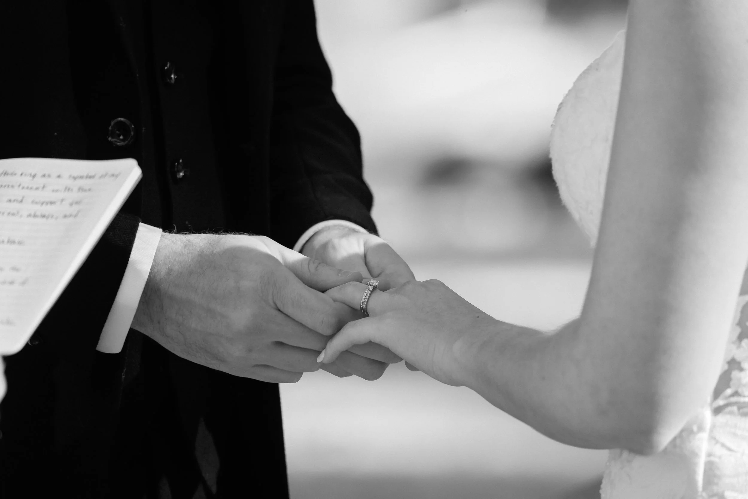 Black and white photo of groom putting the ring on his bride's finger in Yosemite