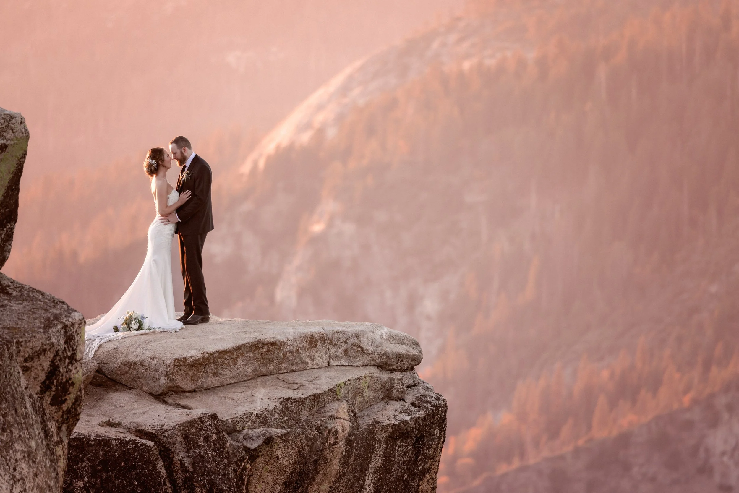 Bride and groom standing on a cliff at Taft Point in Yosemite