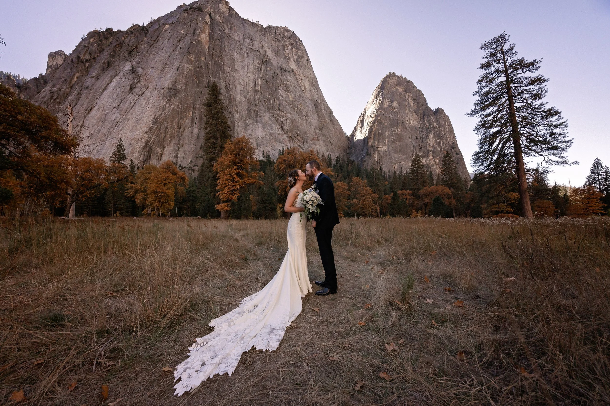 Bride and groom embracing under the granite mountains in Yosemite