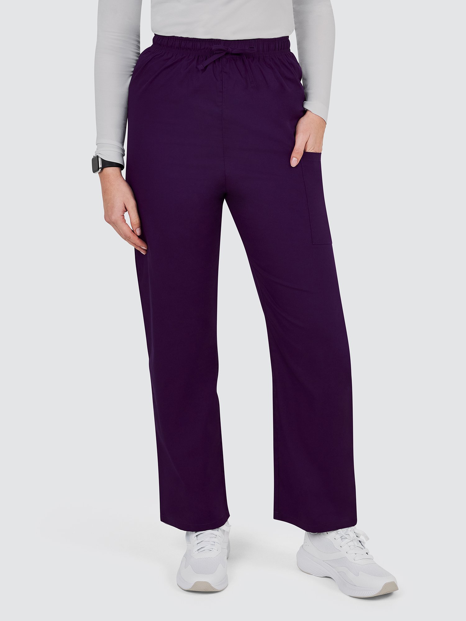A person wearing a long-sleeve shirt, dark purple drawstring pants, and white sneakers is standing against a plain background. The person has one hand in the pants pocket and is wearing a smartwatch.