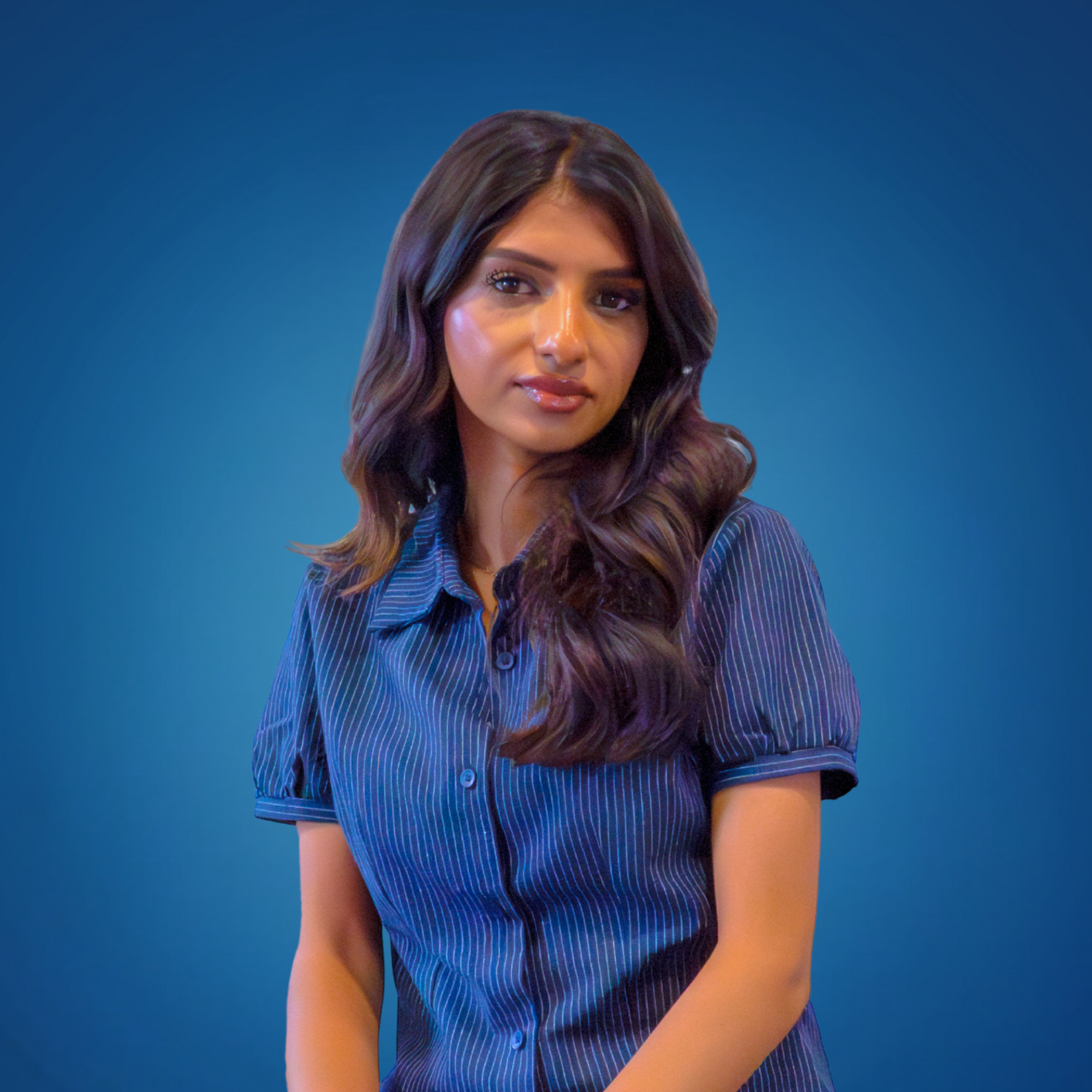 A woman with long, wavy brown hair wearing a navy blue button-up shirt with thin pinstripes, standing against a blue gradient background.