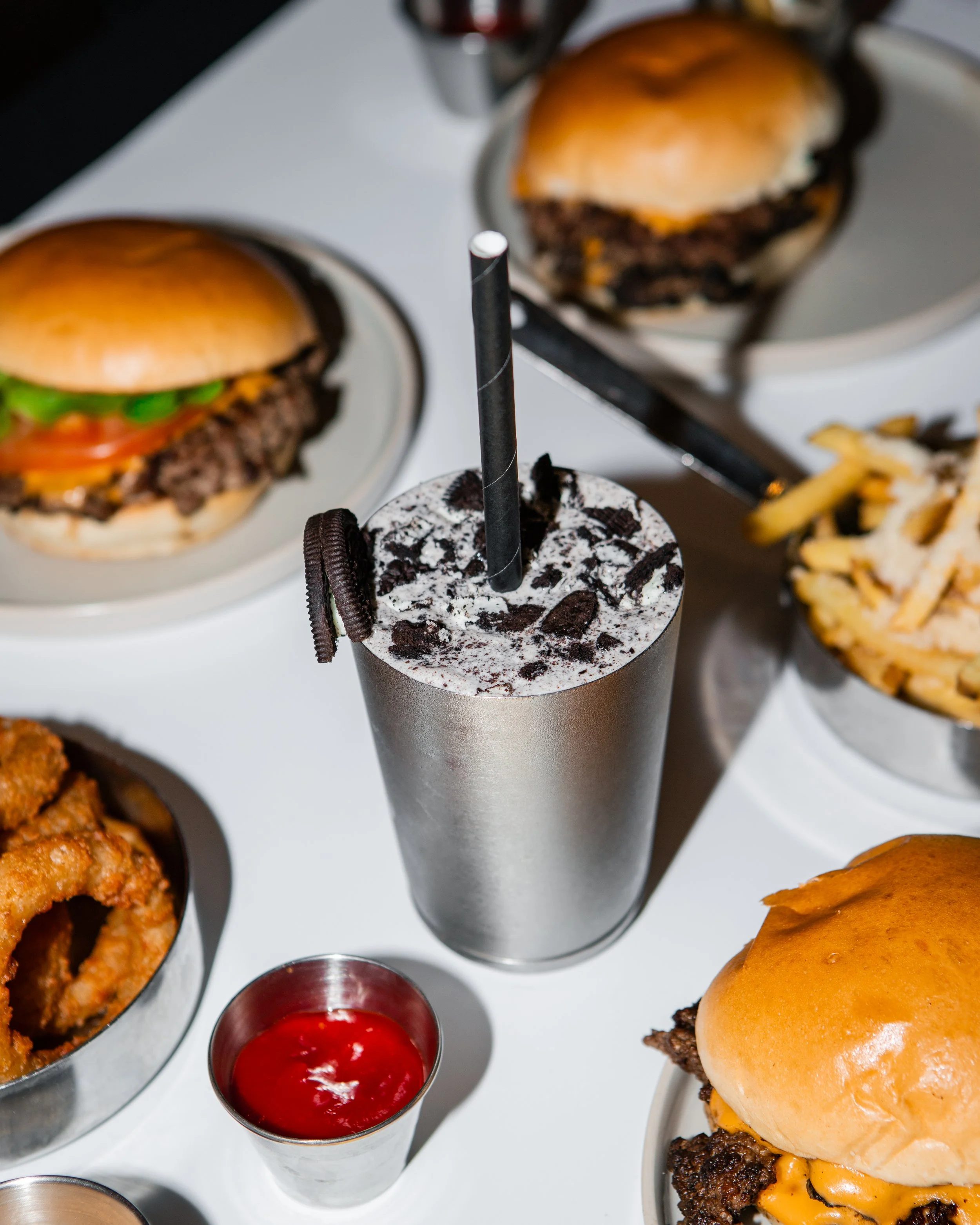 Milkshake mit Oreo-Keksen, umgeben von Cheeseburgers, Pommes, in Berlin. Beef ist von Weiderindern. Beef ist Halal. Auch als vegetarischer Burger zu bestellen.