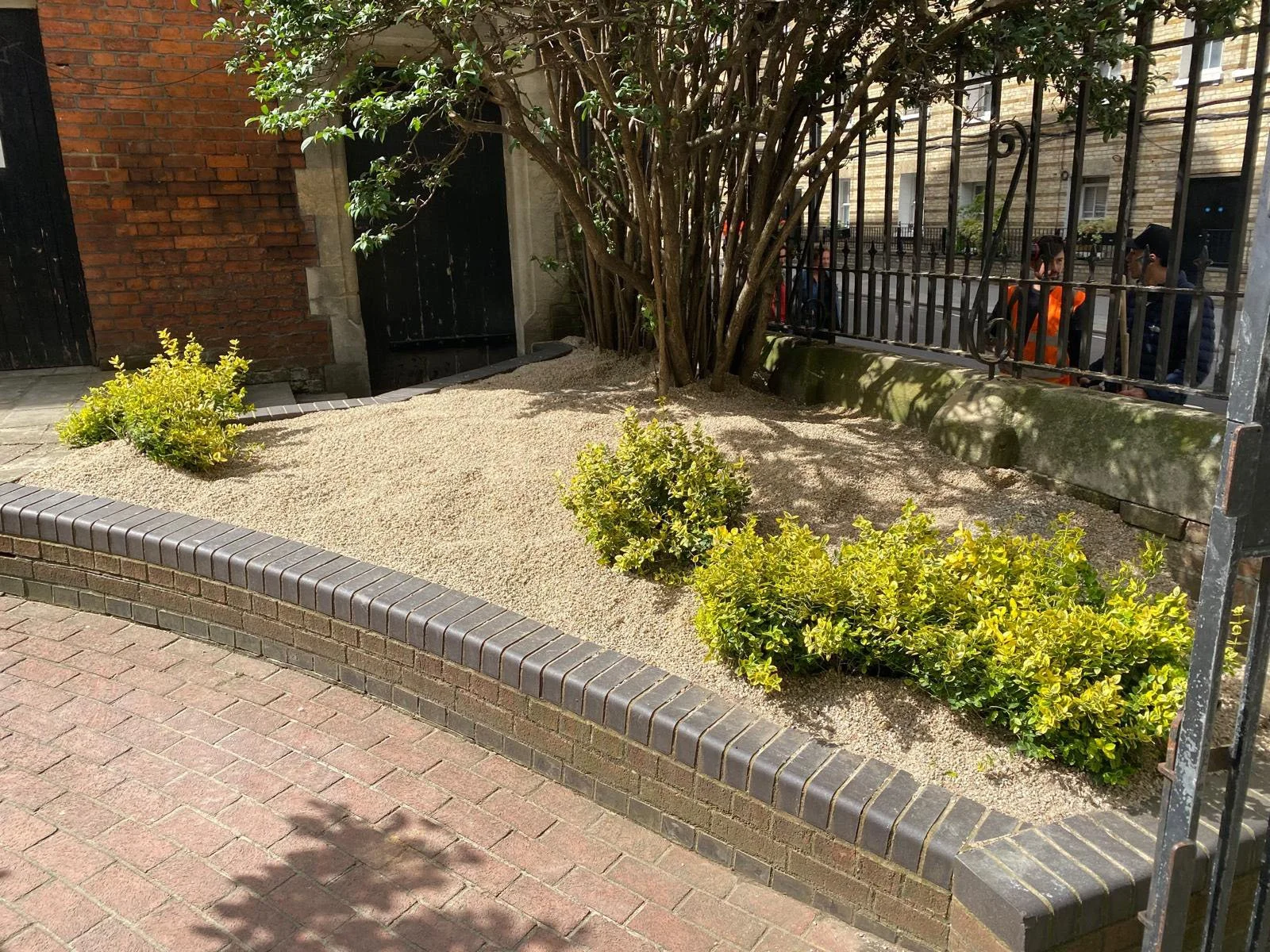 The sand applied flush with the existing 1980s brick planters, as directed by Peter Korn