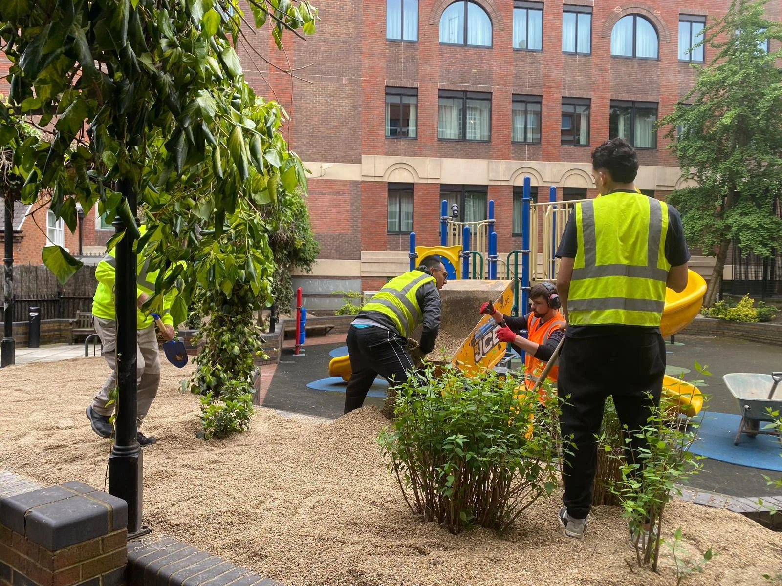 Sand being unloaded into the existing brick planters from the powered barrow
