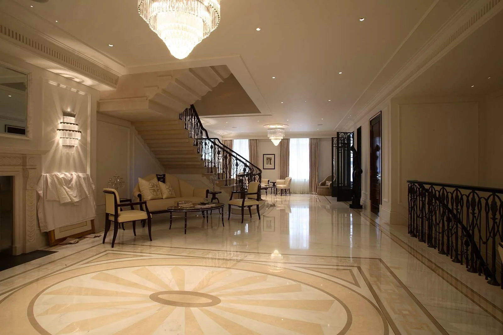 Luxurious hotel lobby with marble floors, crystal chandeliers, ornate staircase, and elegant seating area