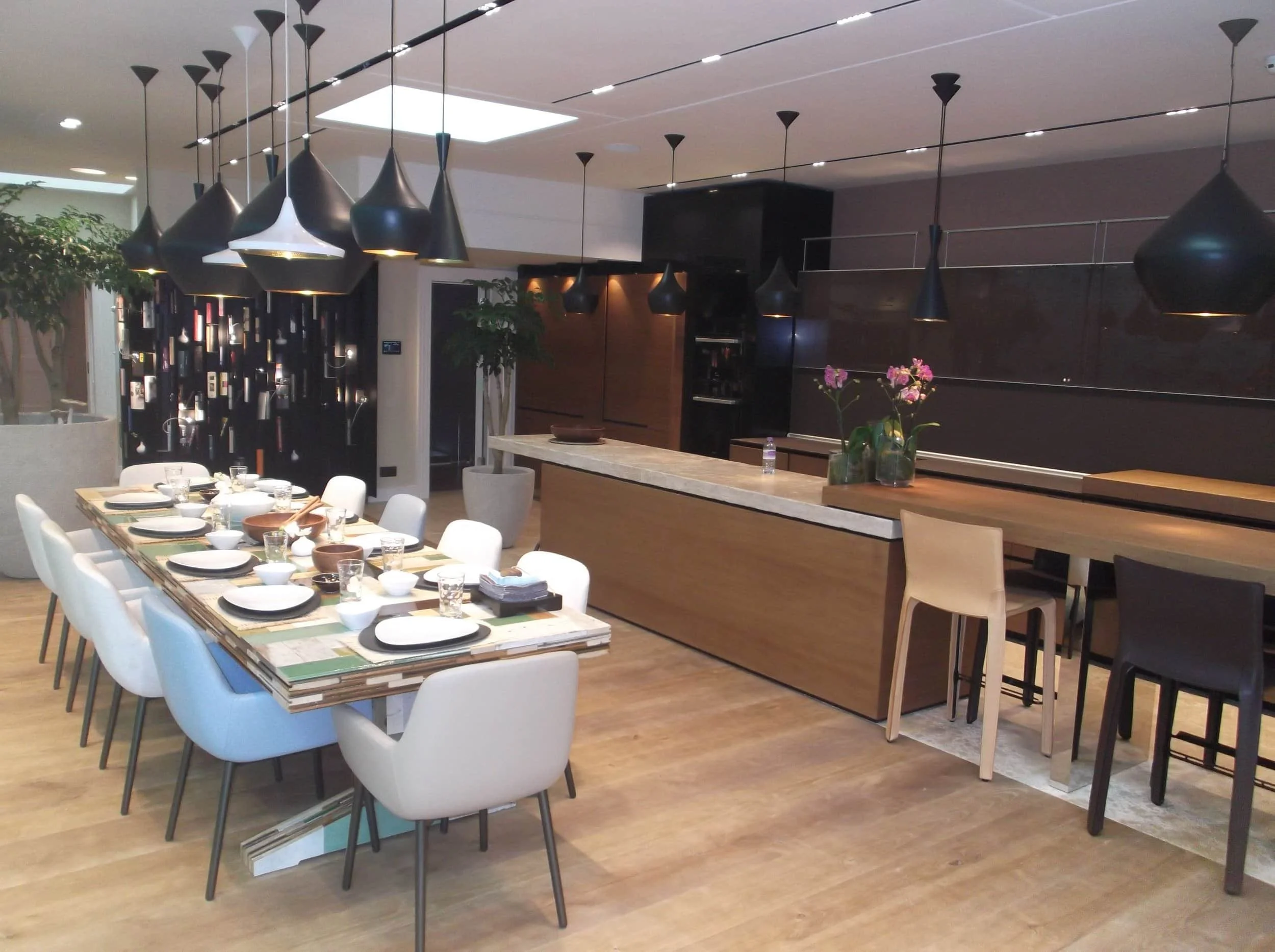 Modern dining room with a set table, bar counter, orchid centerpiece, and numerous black pendant lights