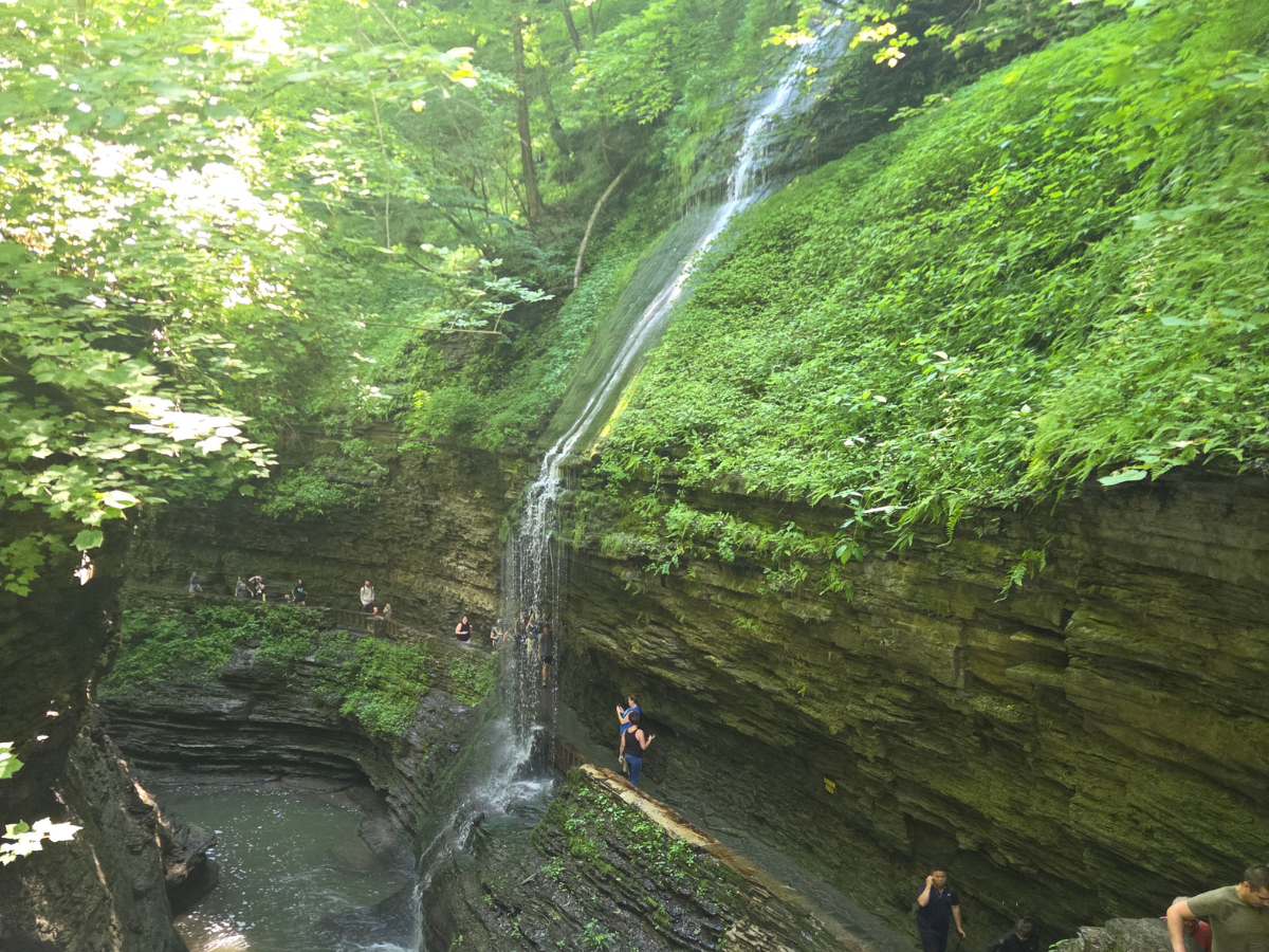 Water flowing down the side of a gorge over a walking path.