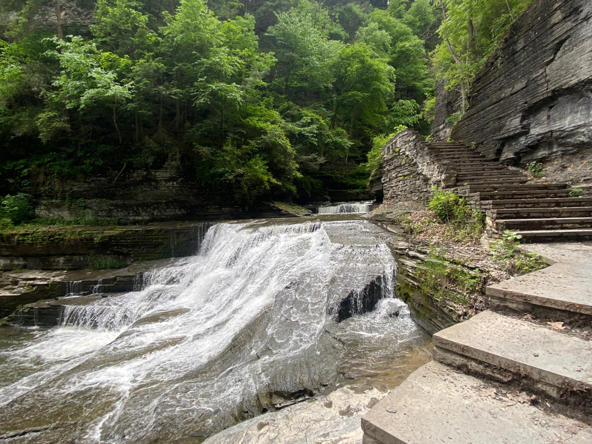 Stairs alongside rushing water flowing down a waterfall.