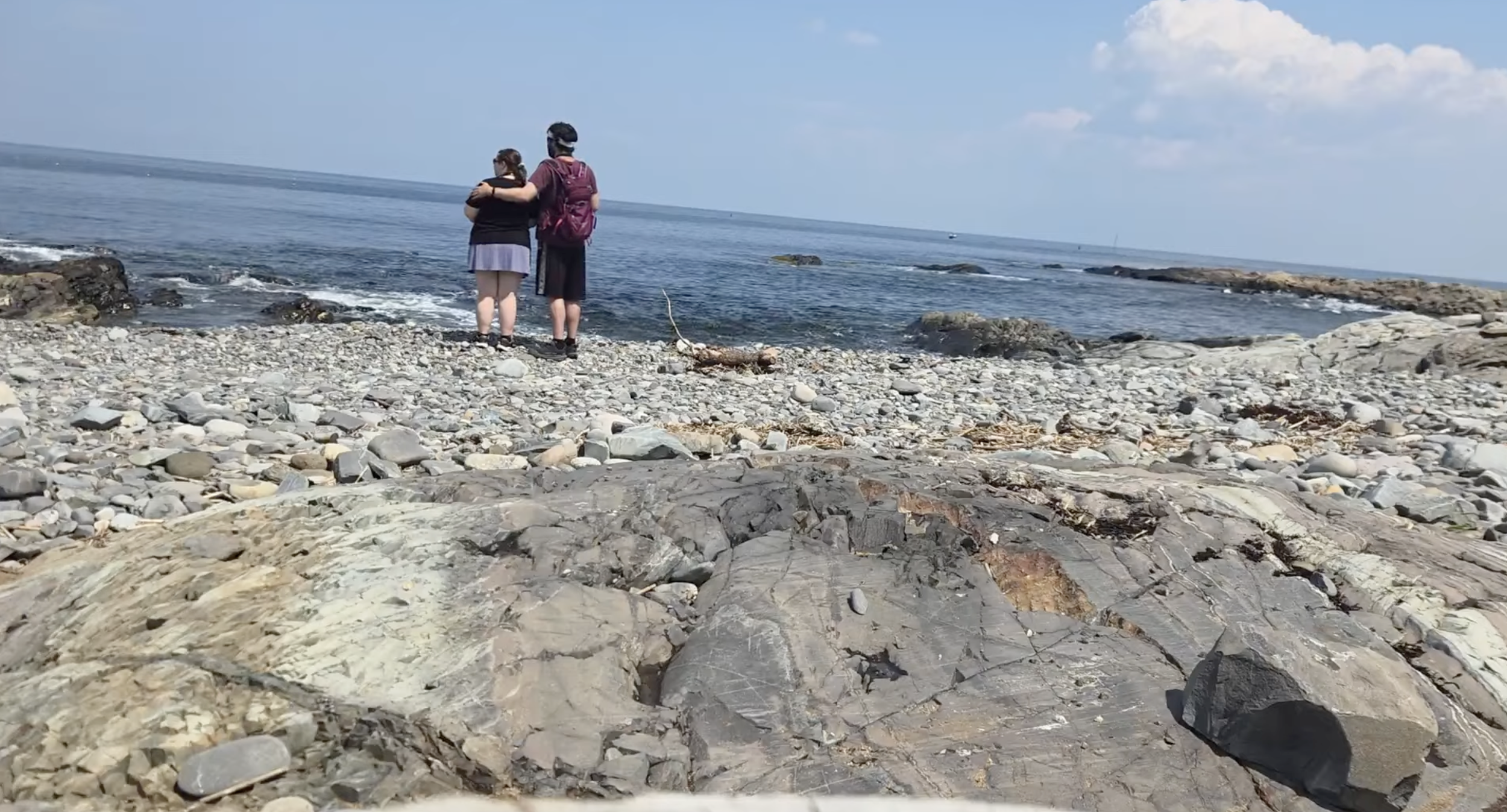 A couple standing on the beach looking at the water