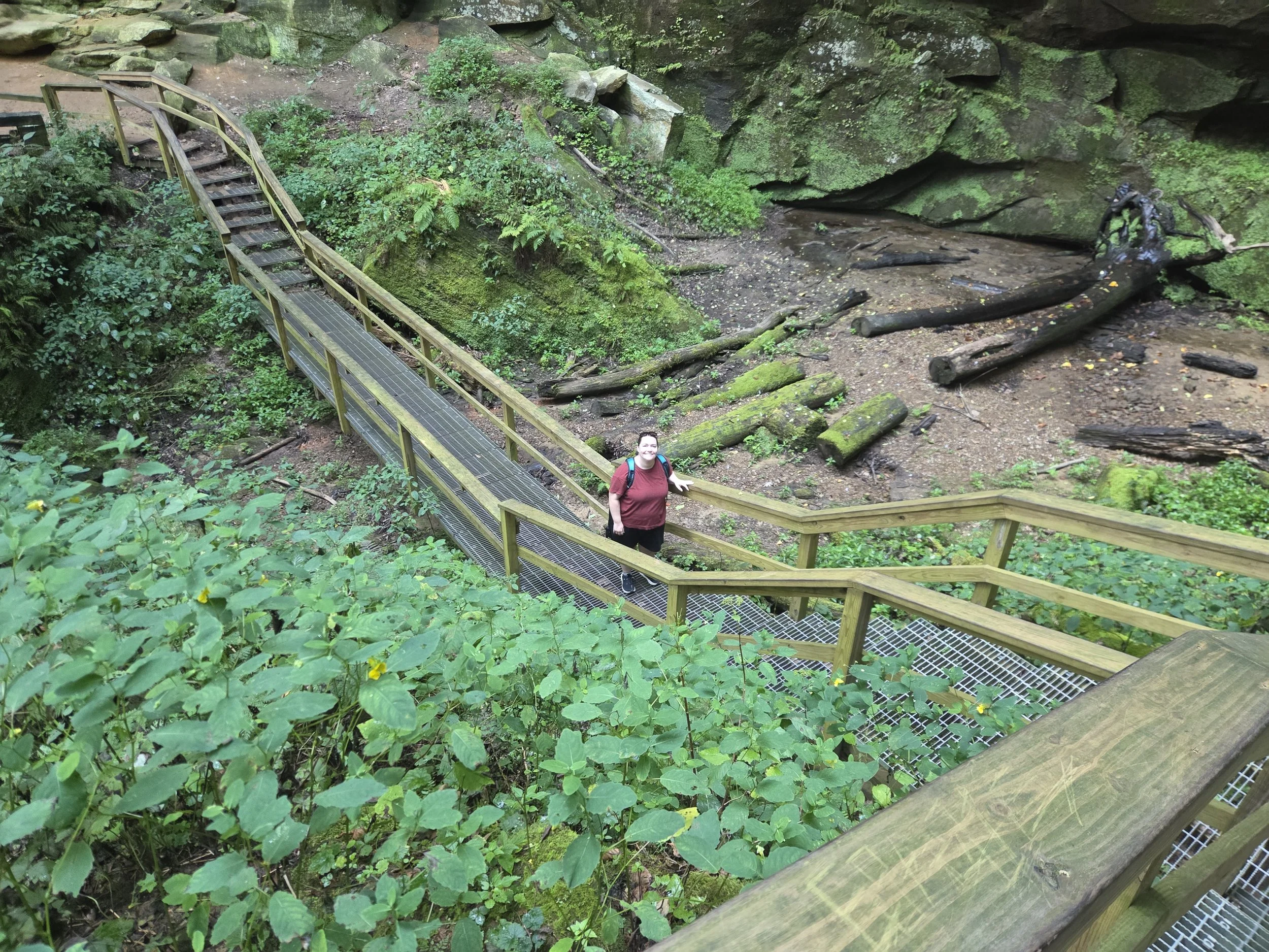 A woman standing in the middle of a wooden bridge along the pathway