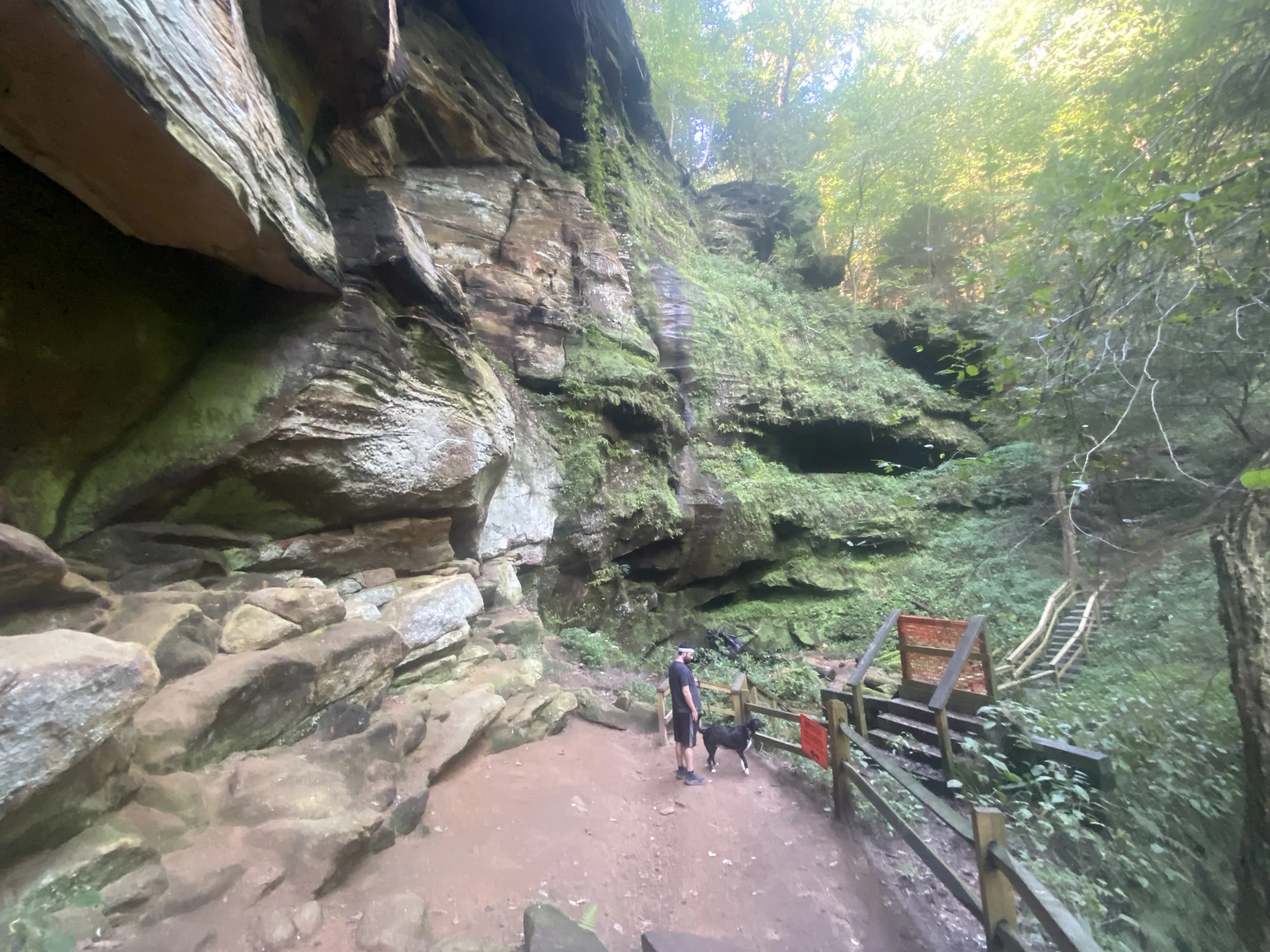 A man with a dog in front of a portion of trail blocked off by gates