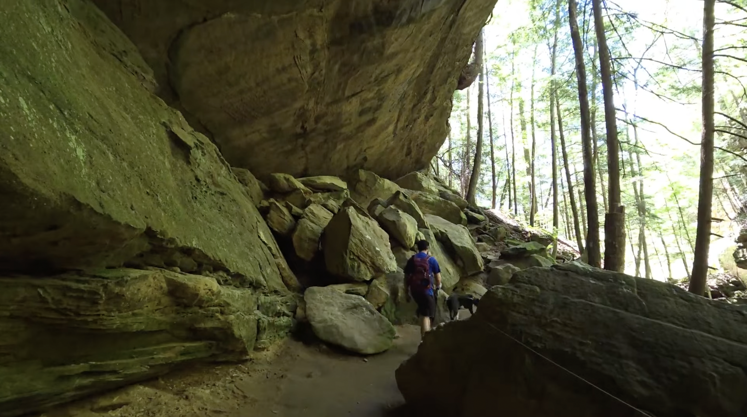 A man standing under a large rock 