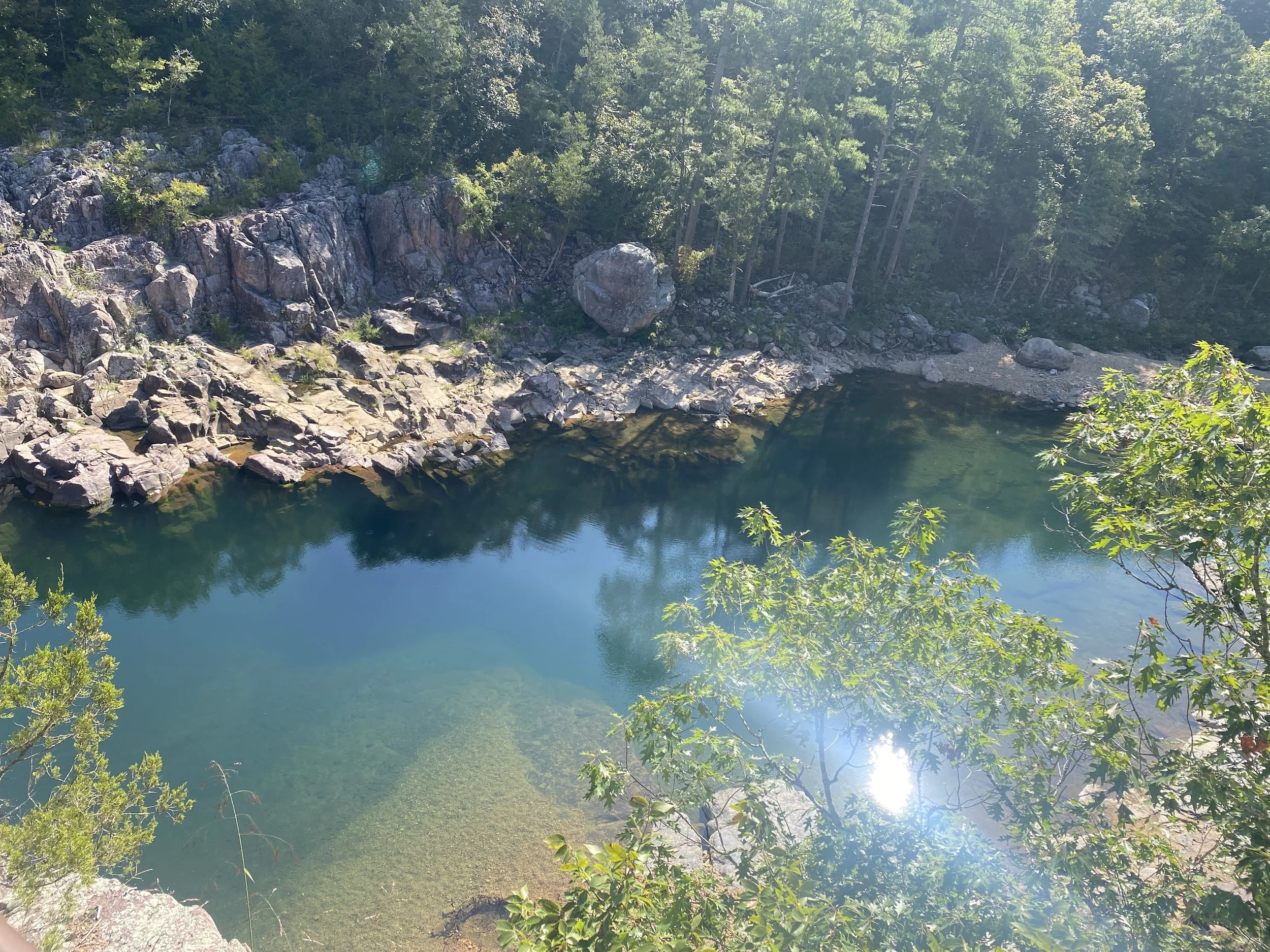 A large clear portion of water in the river surrounded by large rocks.