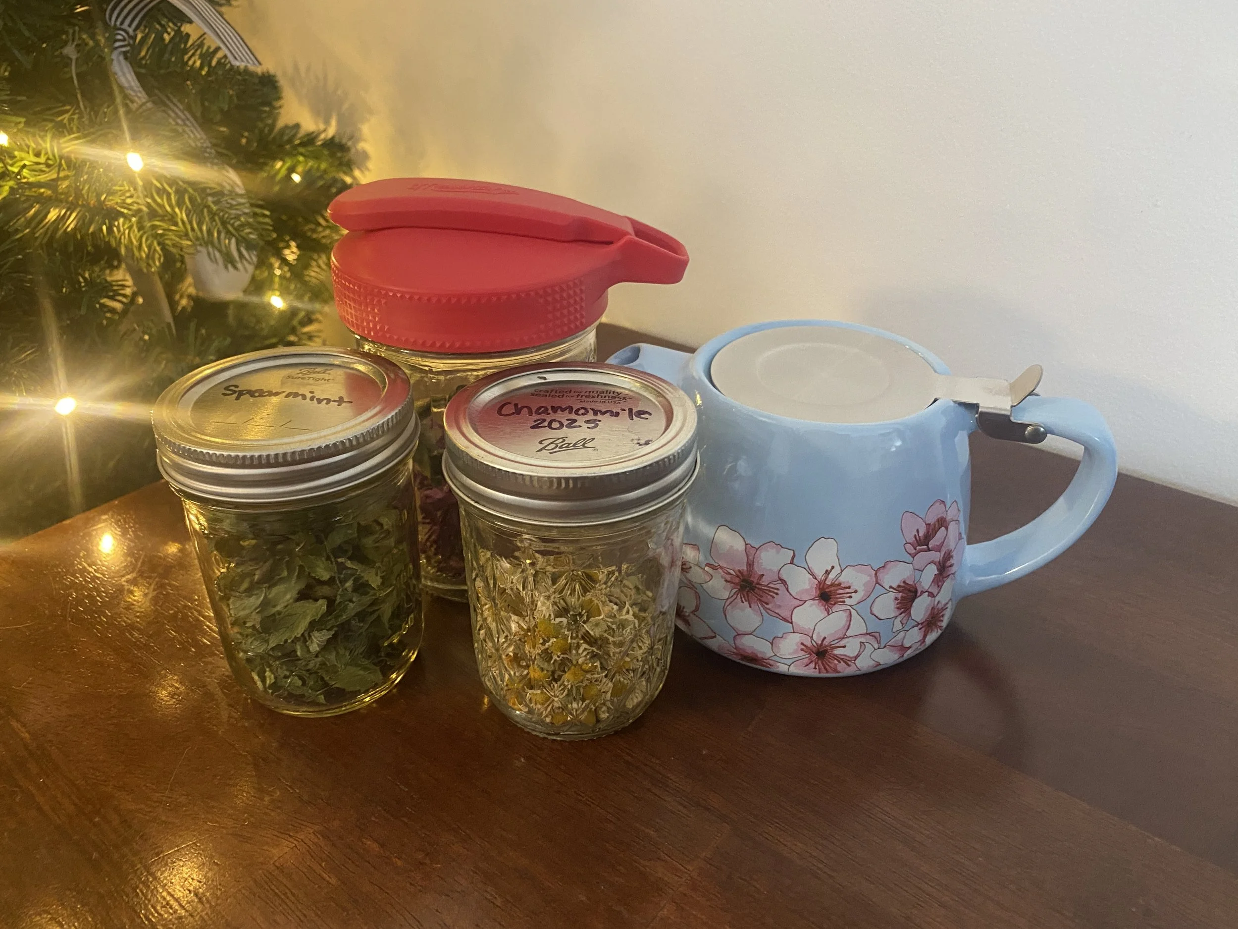 Jars with homegrown tea next to a teapot.
