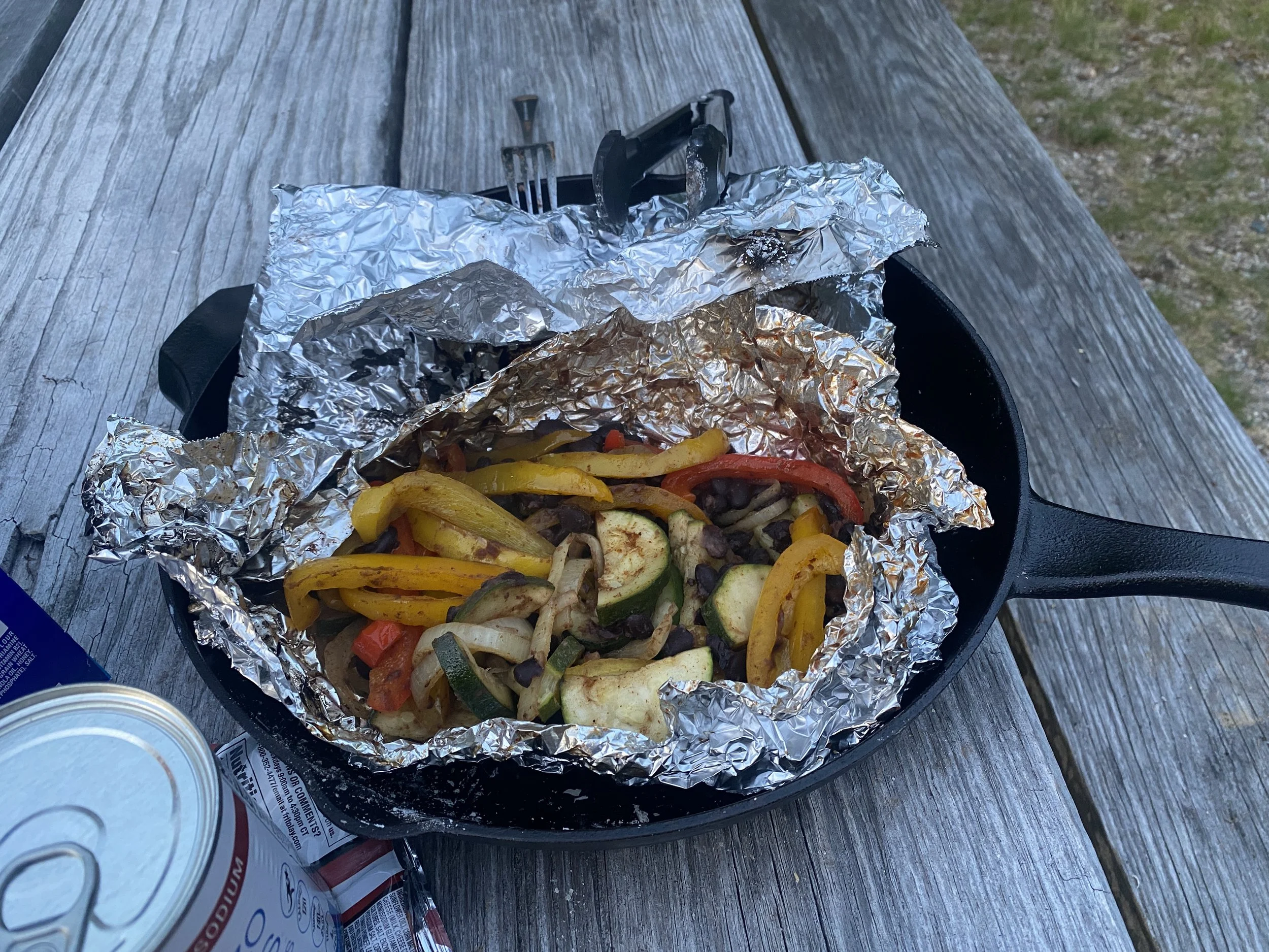 Fajita veggies sitting in aluminum foil inside of a cast iron skillet.