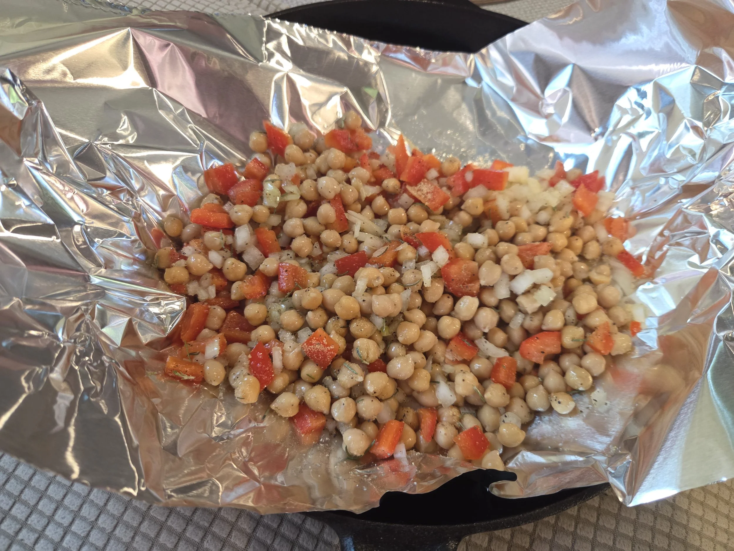 Chickpeas and vegetables sitting on aluminum foil.