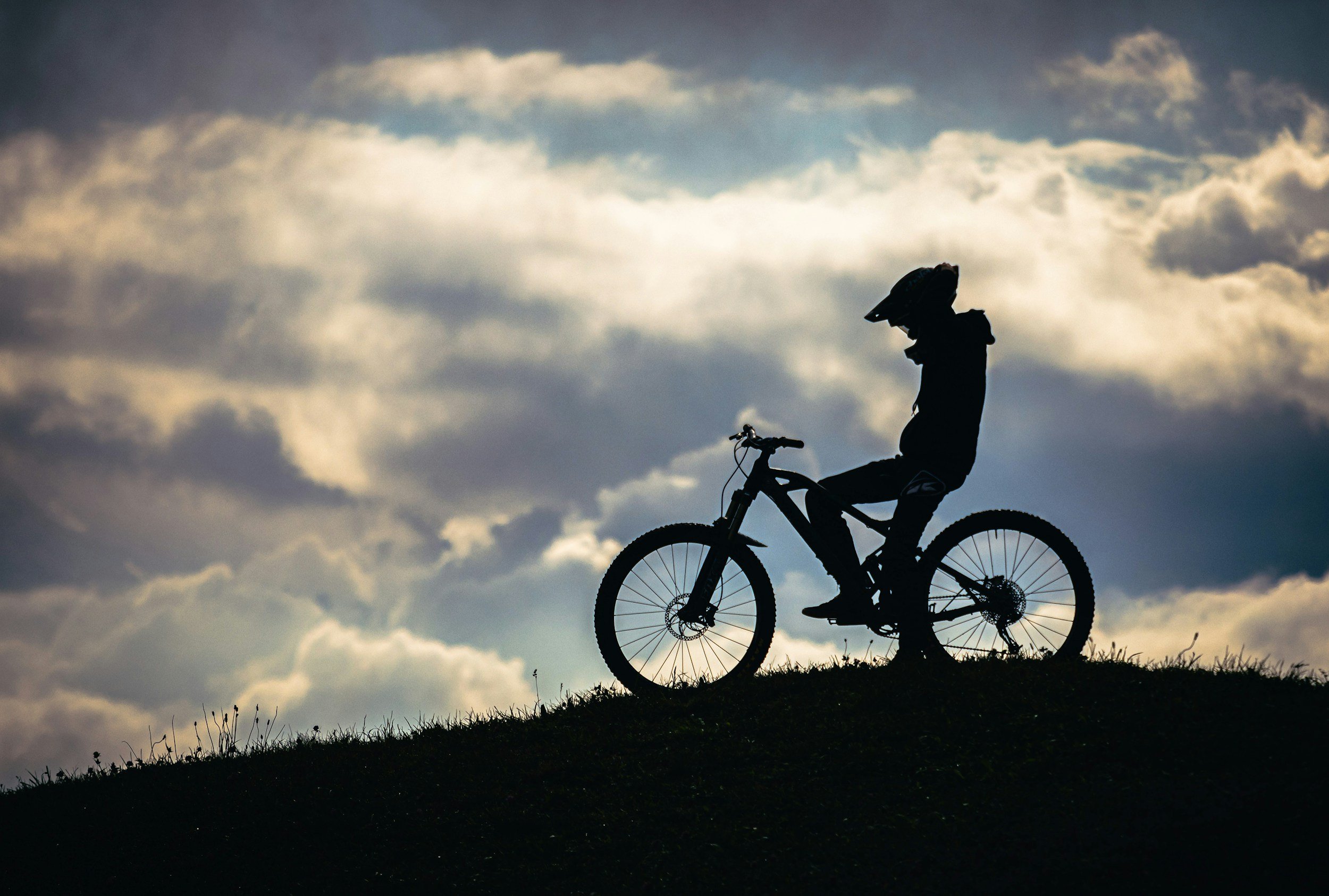An image of a blue sky and a person on a bike showing only her shadow.