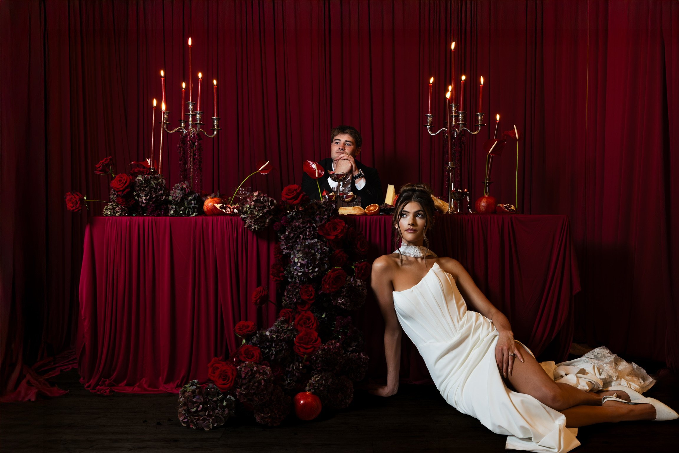 High-end wedding design featuring deep red velvet draping, elegant table decor, and silver candelabra.