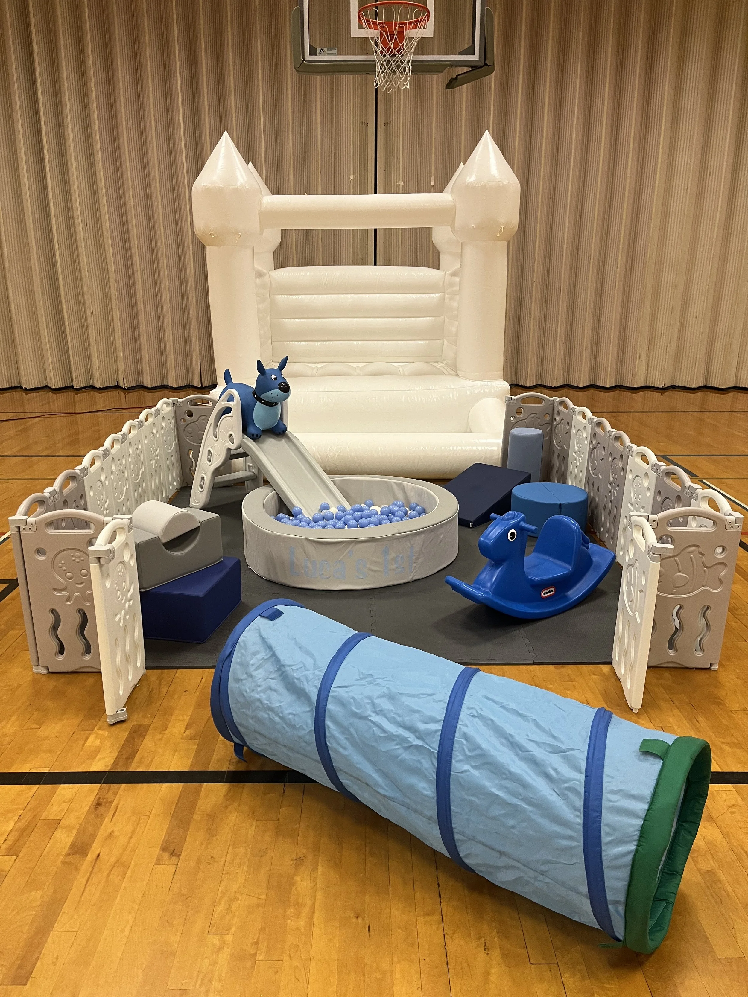 Light blue foam play structure with steps and ramp, filled with white plastic balls, in a child's room with white brick wall backdrop, moon and star decor, curtains, and a white dresser.