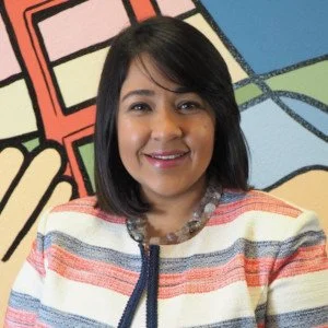 Headshot of a Latina woman with a black bob hairstyle, smiling in a red, white, and blue striped blouse