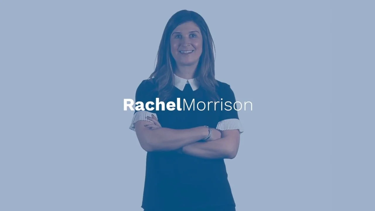 A woman with shoulder-length brown hair smiling, standing with arms crossed, wearing a black dress with white collar and sleeve accents. The text 'Rachel Morrison' appears in front of her.