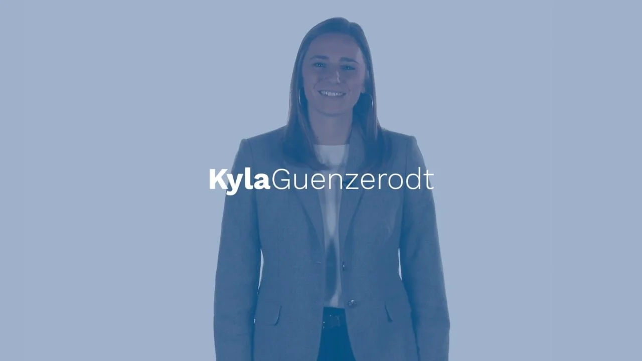A woman in a gray blazer and white shirt smiling at the camera with blue background and text 'Kyla Guenzerdt' on the image.