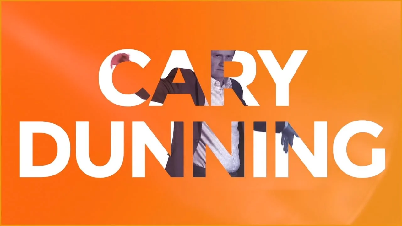 A promotional graphic with the text 'CARY DUNNING' in large white font over an orange background, with a man in a suit and white shirt partially visible behind the text.