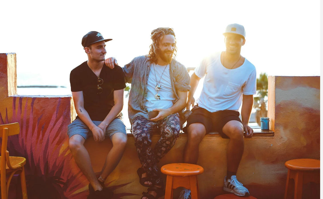 Three men sitting on a ledge outdoors, enjoying community as they strive to stay clean and sober after leaving rehab or incarceration.