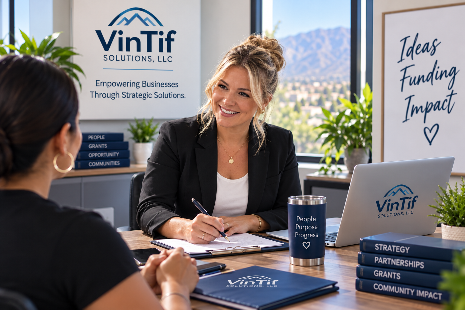 Two women having a business meeting at a wooden table in an office. One woman is smiling, holding a pen, with a laptop and documents in front. The office has green plants, a window with a city view, and displays with the logo VinTif Solutions, LLC and slogans about ideas, funding, and impact.