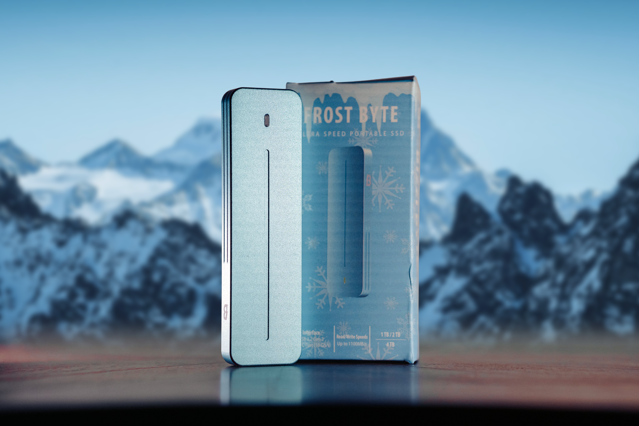 A Frost Byte external solid-state drive with a snowflake design, standing upright on a wooden surface, with mountain peaks in the background.