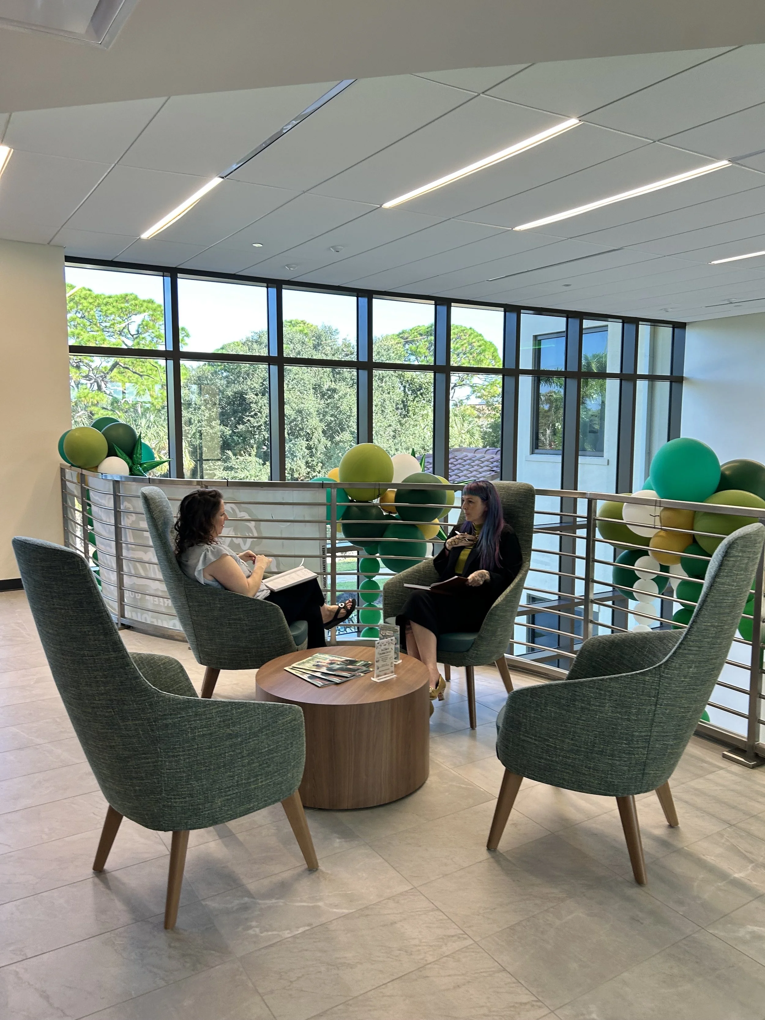 A group of people having a meeting at a wooden table in a modern office with shelves and lighting.