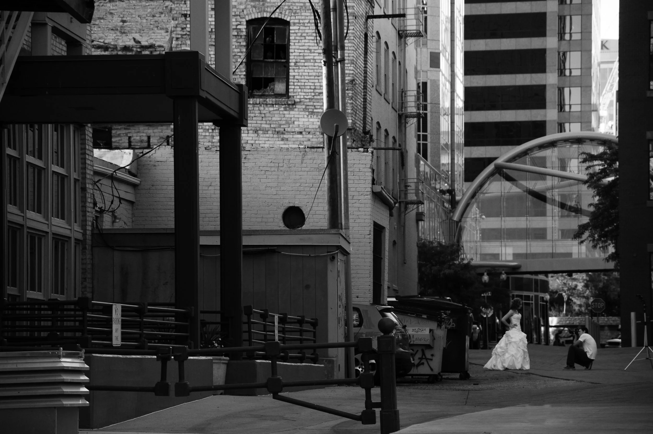 A woman in a white wedding dress being photographed in an alleyway.