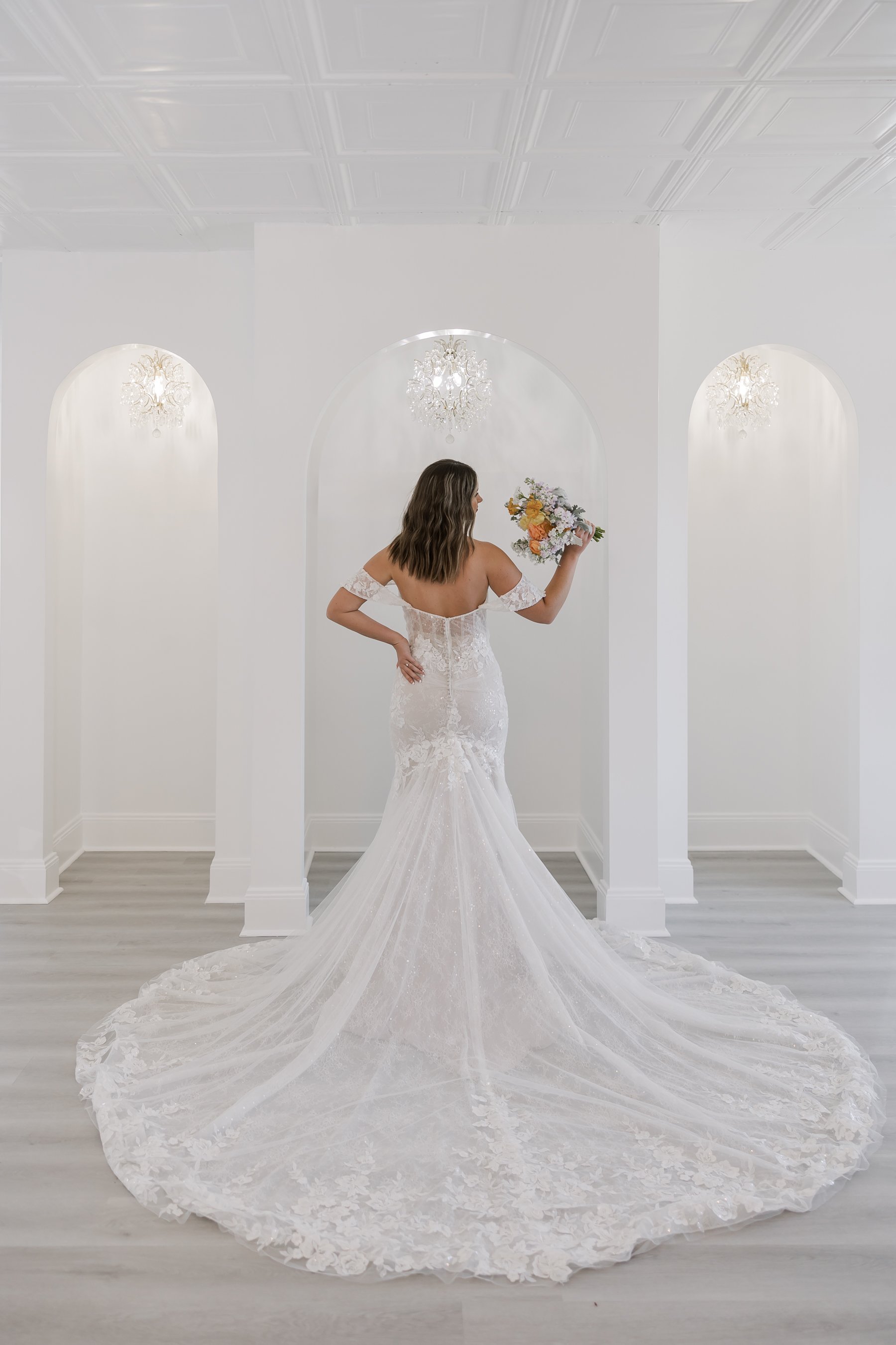 A bride poses in front of the built in dress rack inside the Bridal Suite at The Gallery House