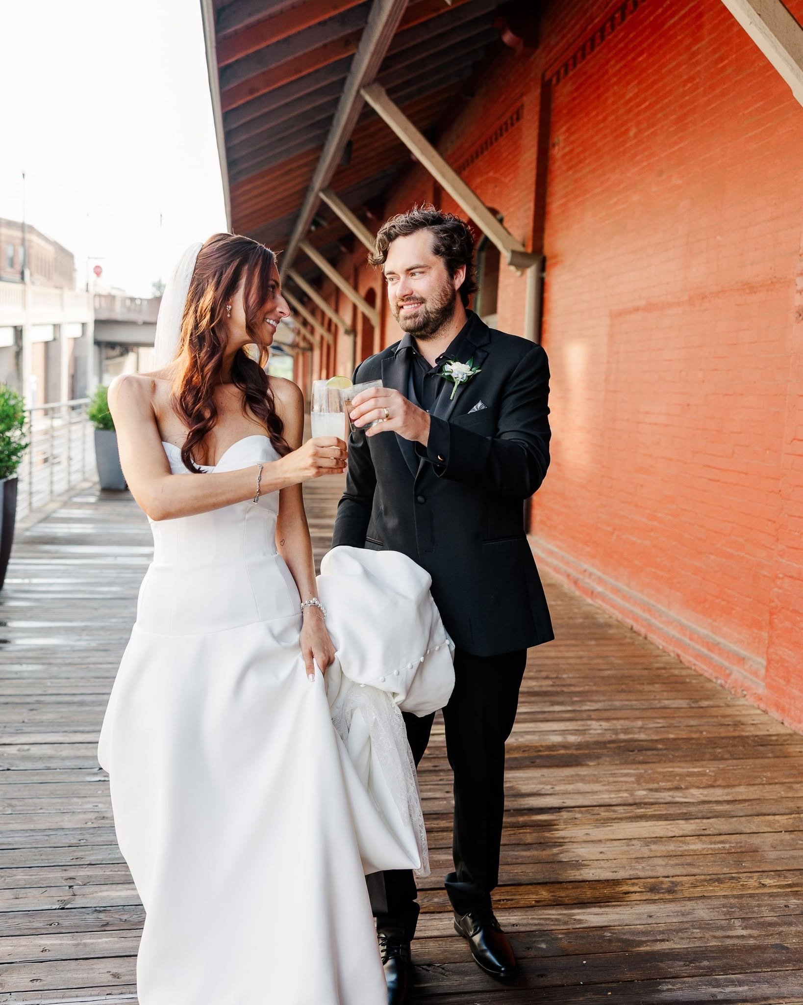 Bride and groom toasting with drinks on the outdoor boardwalk at Jackson Terminal, a historic wedding venue in Knoxville’s Old City.