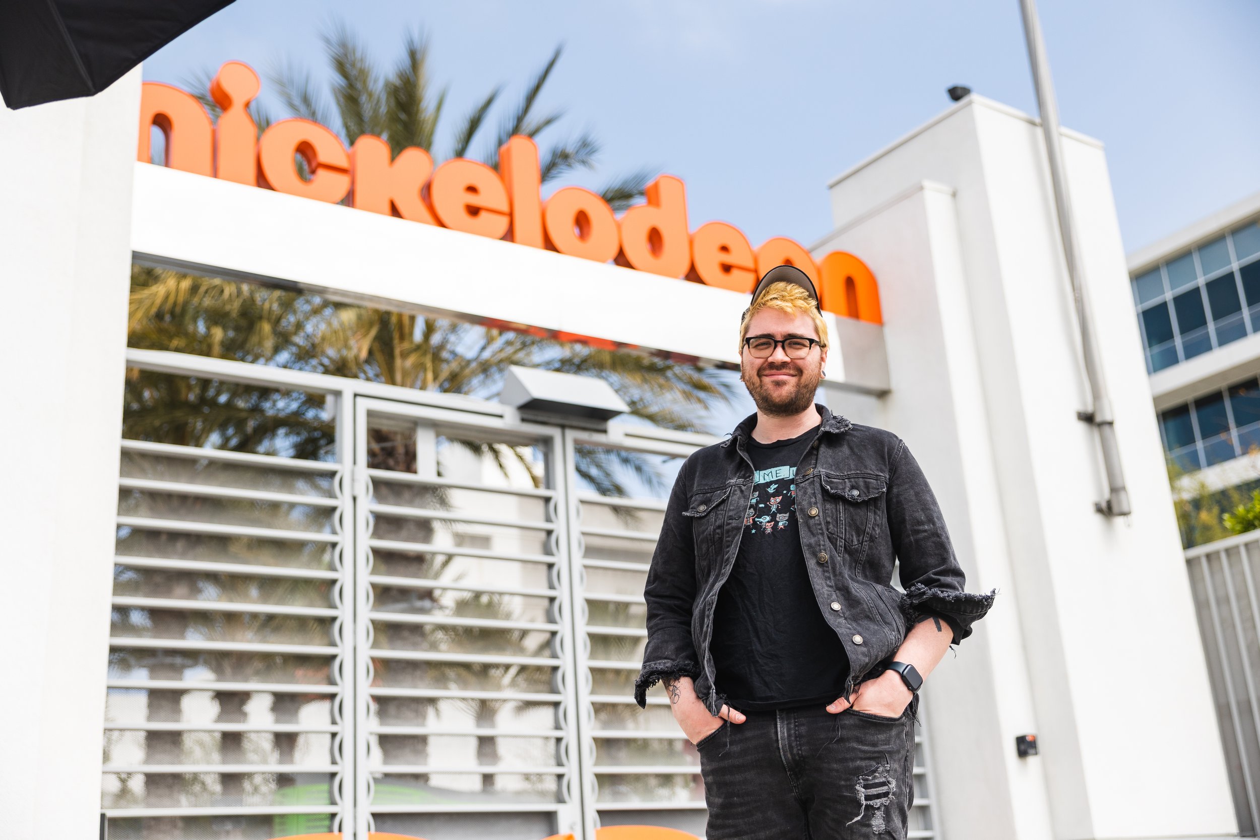 Person standing in front of Nickelodeon building, wearing casual clothes and a hat.
