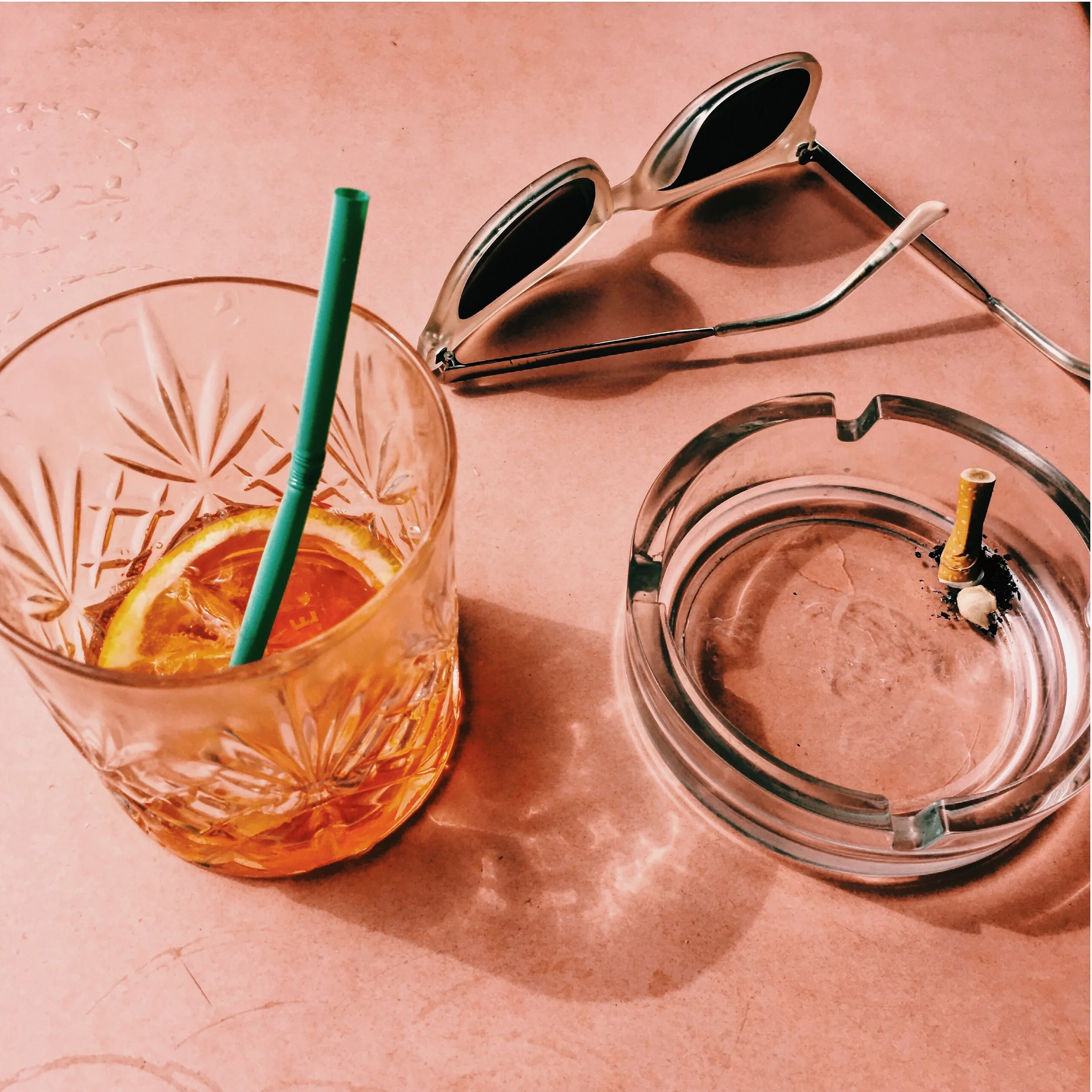 Ashtray with a cigarette, sunglasses and a cocktail glass - Photograph by Noemi Moreno
