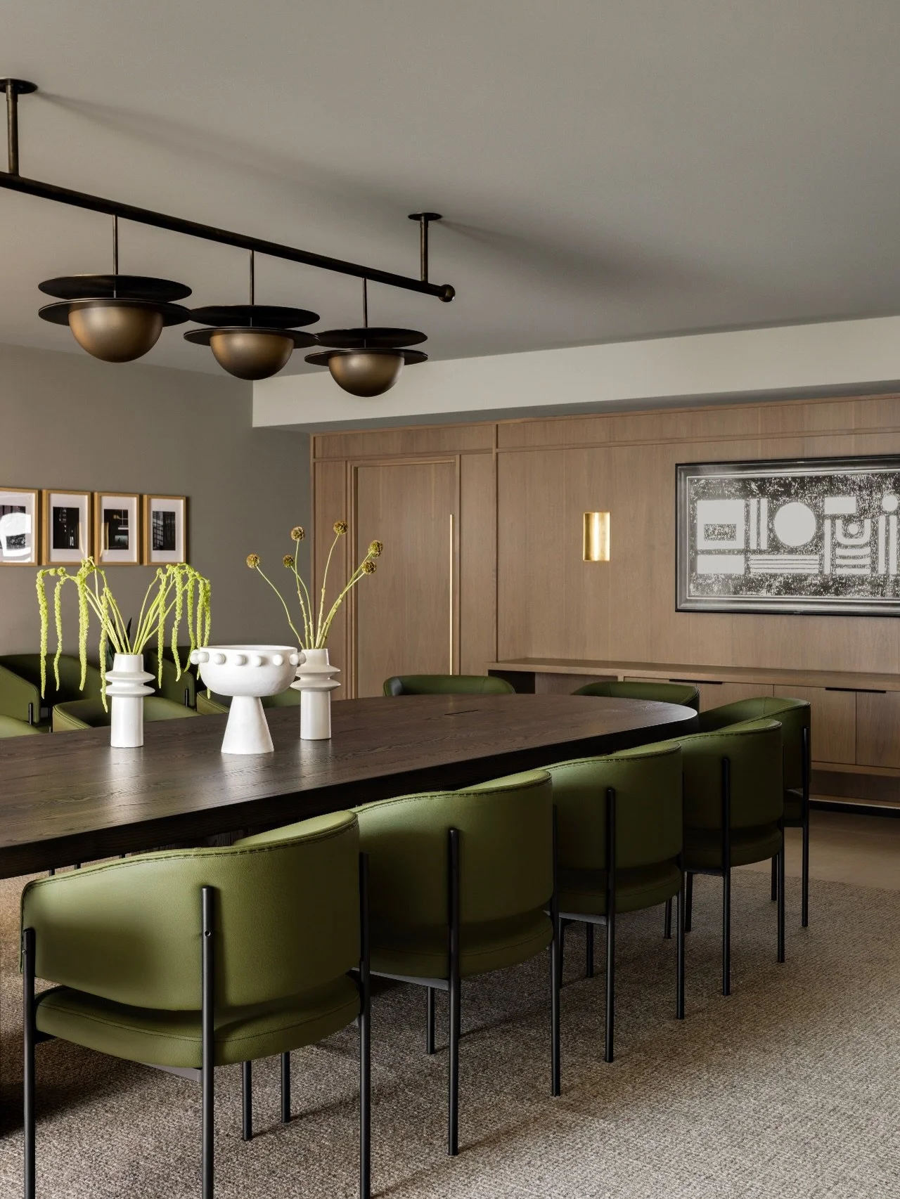 Boardroom. At #AVDCalgaryHouse, we envisioned a boardroom that feels warm, refined, and intentionally layered. A fully custom millwork wall conceals seamless storage, while a softly curved custom table anchors the space. A sculptural architectural li