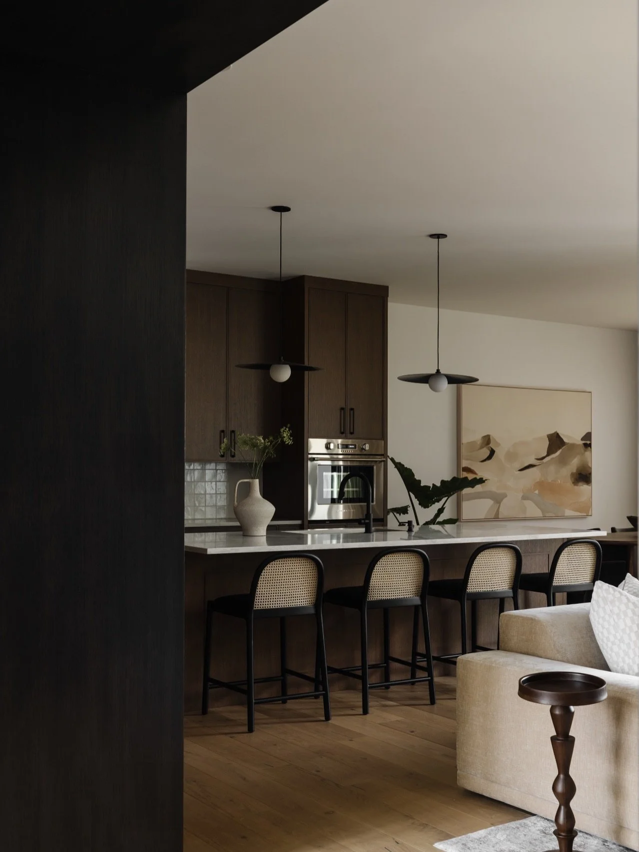 Kitchen. A true showstopper at #AVDParkHill. This dark and moody kitchen is enveloped in richly stained oak cabinetry, grounded and warm in tone. A simple square tile wraps the backsplash and hood, creating a quiet contrast that lets the materials sp