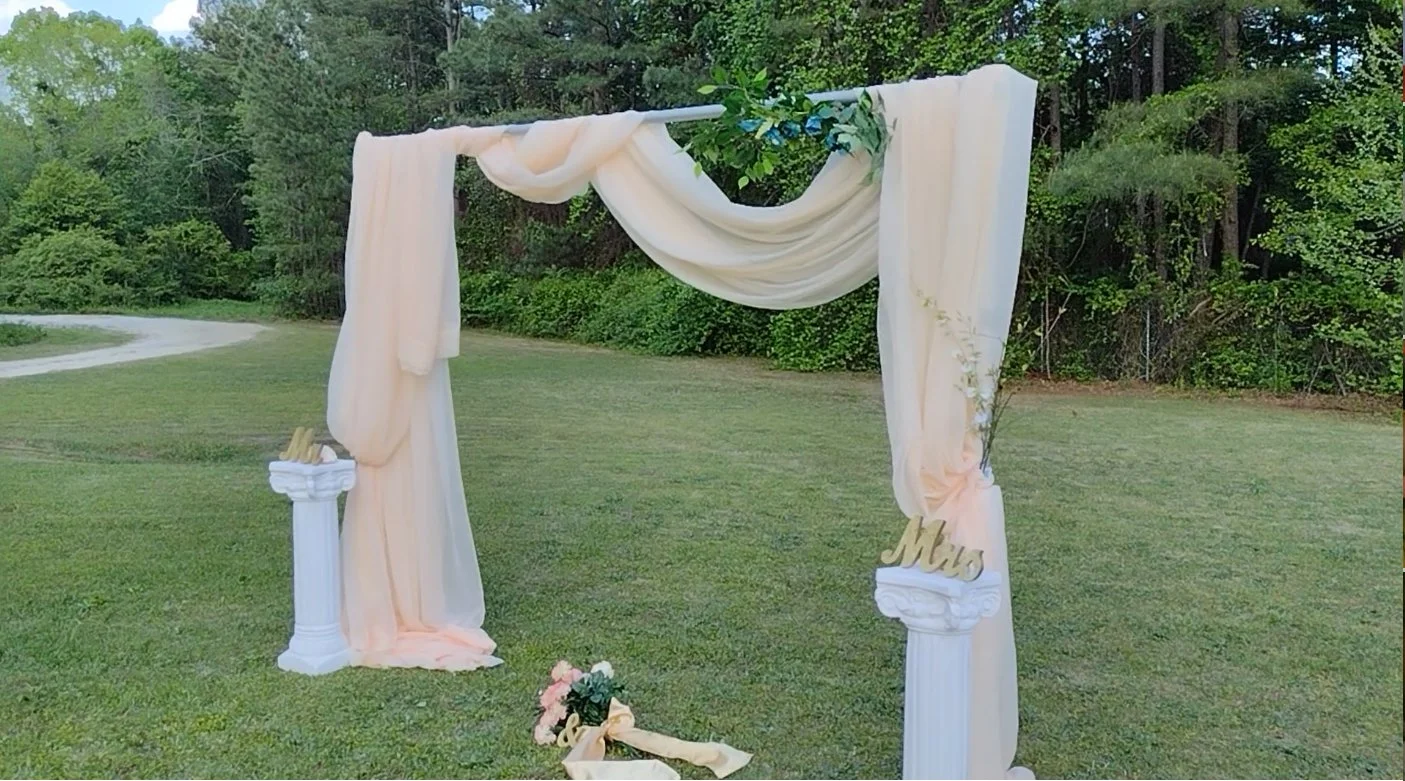 Elegant ivory draped archway with floral accents — the perfect backdrop for timeless outdoor ceremonies designed by Moments Planning.