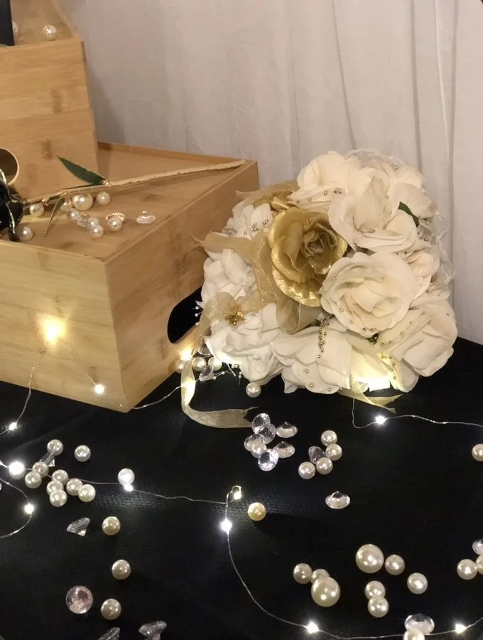 A handcrafted white and gold bridal bouquet accented with pearls and fairy lights — a signature Moments Planning original design.