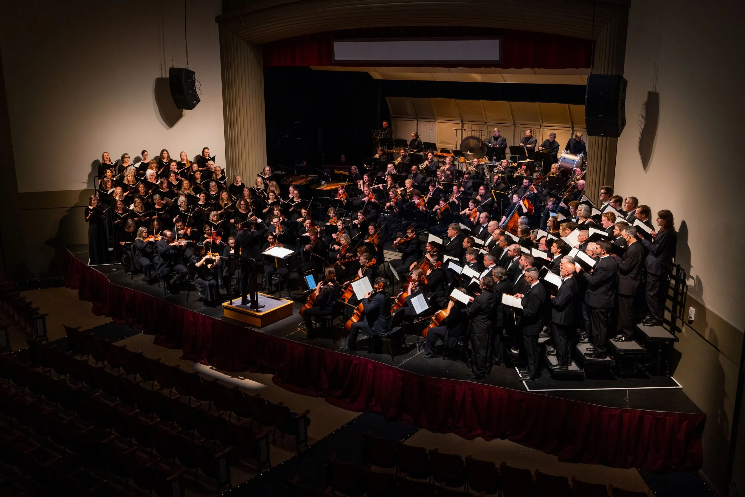 An orchestra and choir are on stage performing together during a dress rehearsal