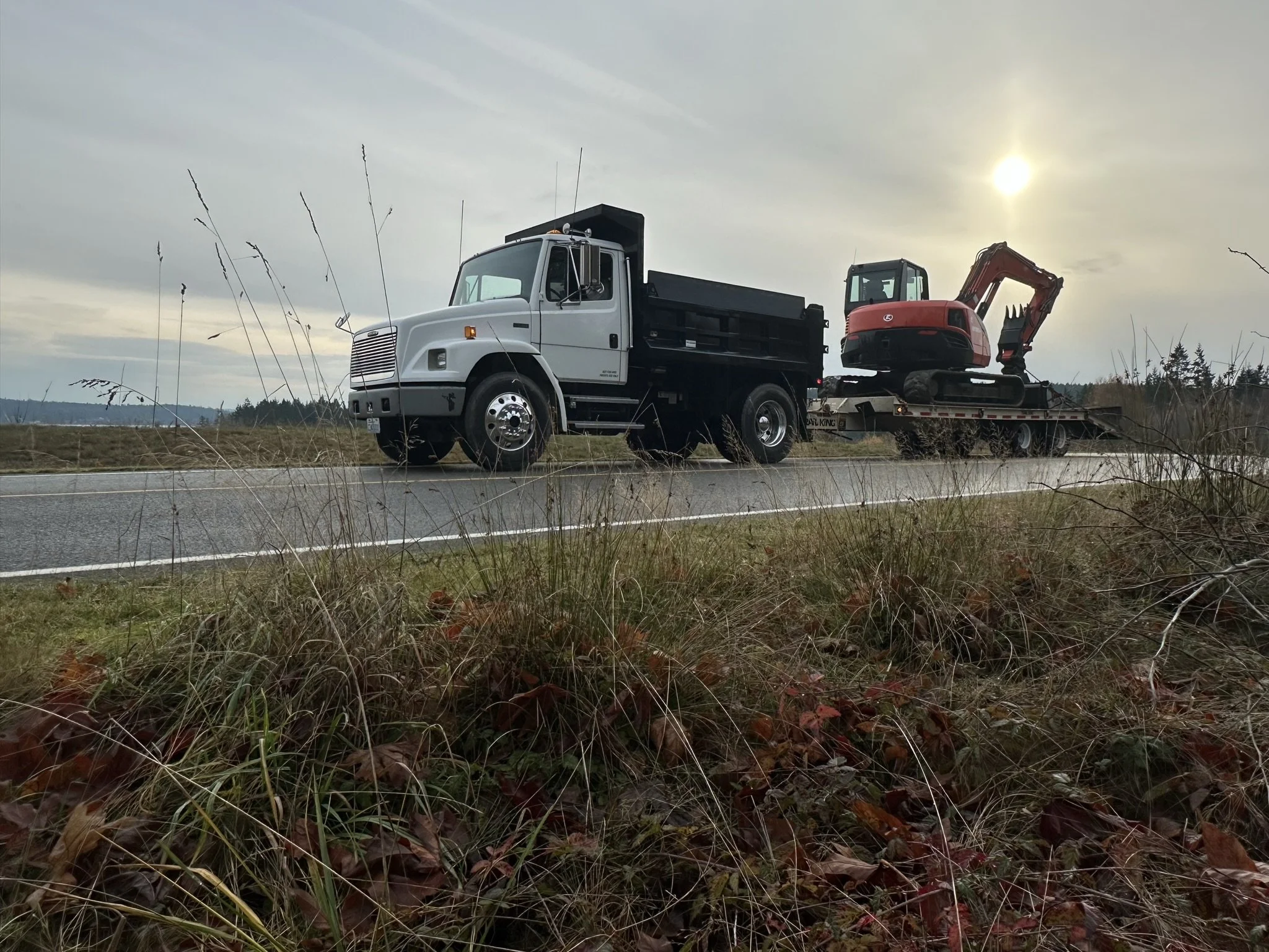 NW Development and Underground dump truck hauling the small excavator at a waterfront project